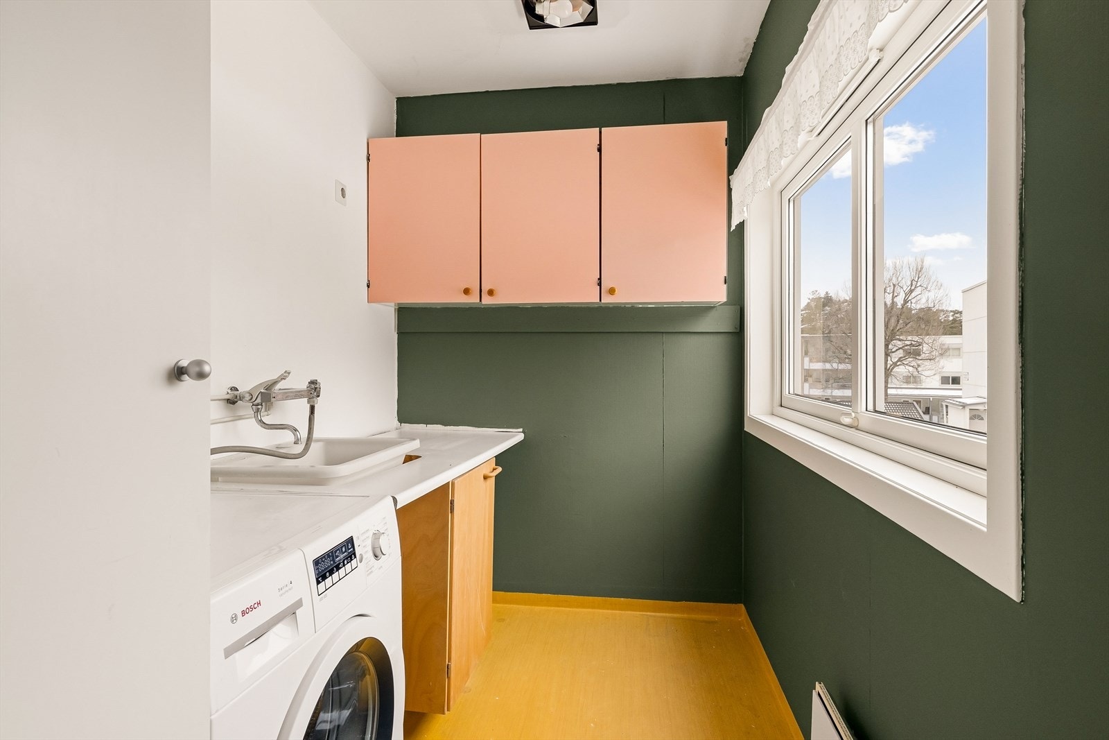 Eldre, men praktisk vaskerom. Innredet med skyllekum, benkeplate, skaper og opplegg for vaskemaskin. Galleribilde