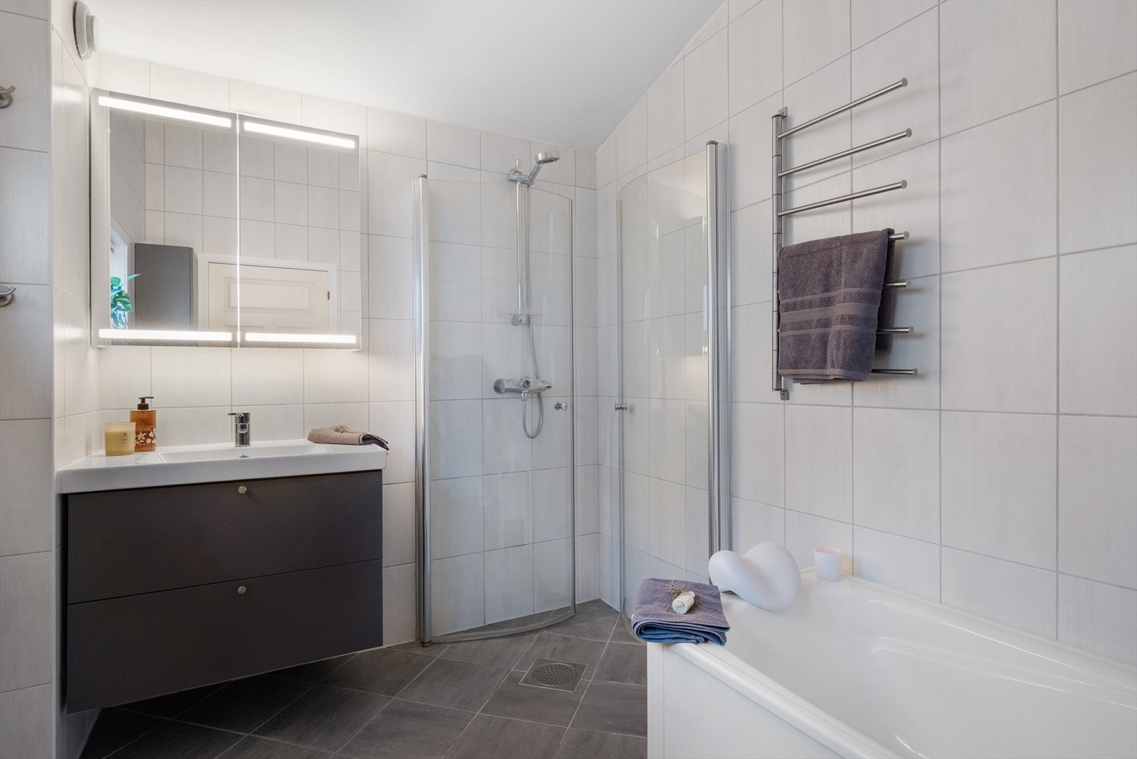 Badet har stilrent uttrykk med flislagte overflater og dusjløsning med glassdører. Galleribilde