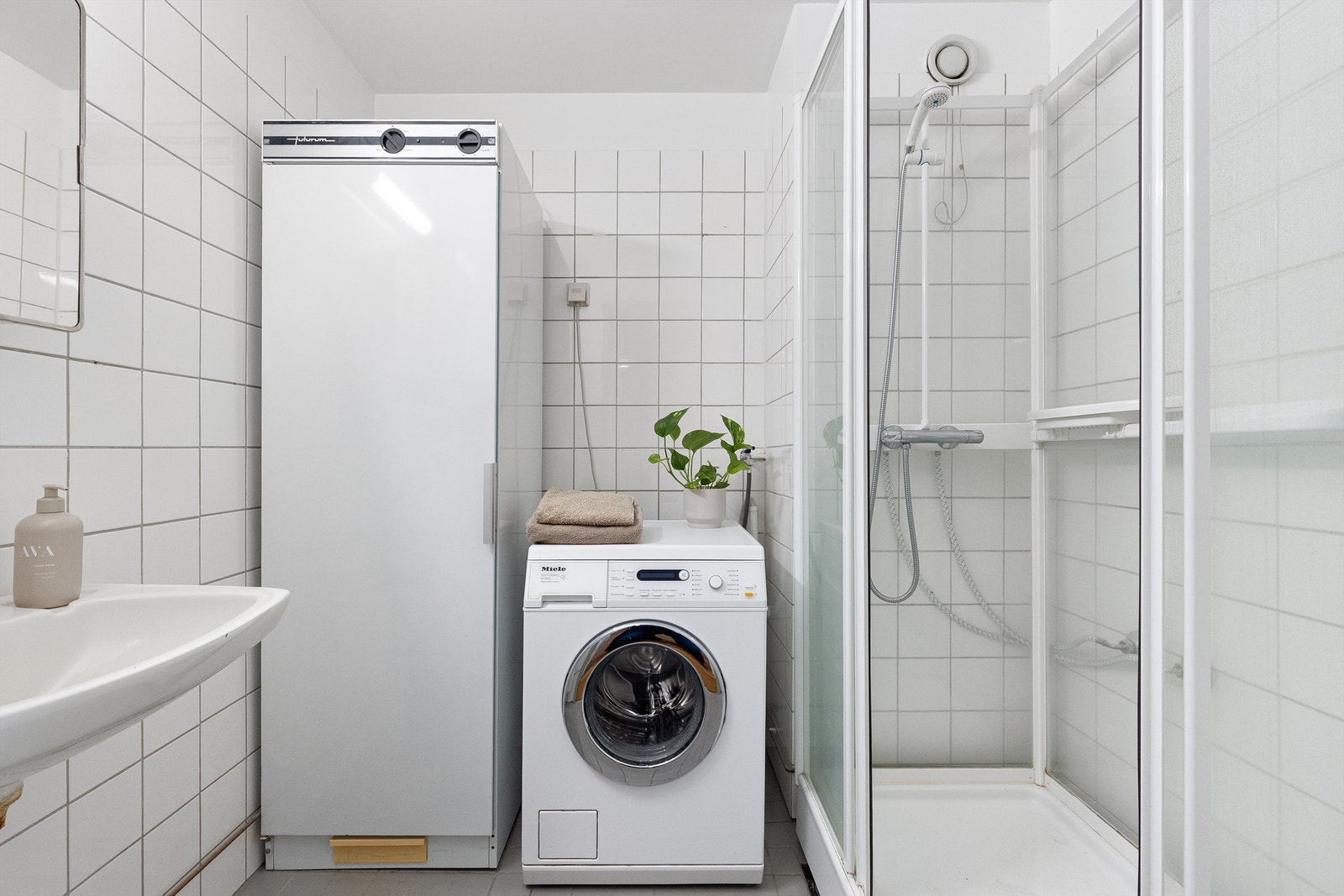 Flislagt bad fra byggeår med dusjkabinett, tørkeskap, servant og opplegg for vaskemakin Galleribilde