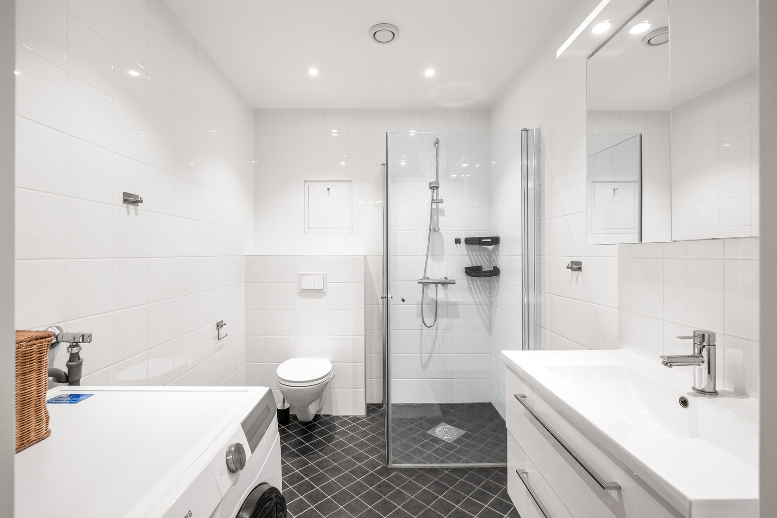 Romslig baderom bestående av servant, veggfestet klosett med innebygget sisterne og opplegg for vaskemaskin. Galleribilde