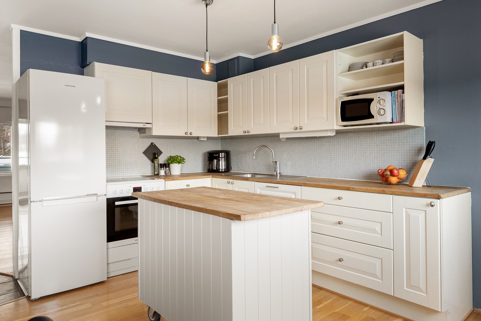 Kjøkkeninnredningen byr på rikelig skap- og benkeplass, og den praktiske, mobile kjøkkenøya gir ekstra fleksibilitet i rommet. Galleribilde