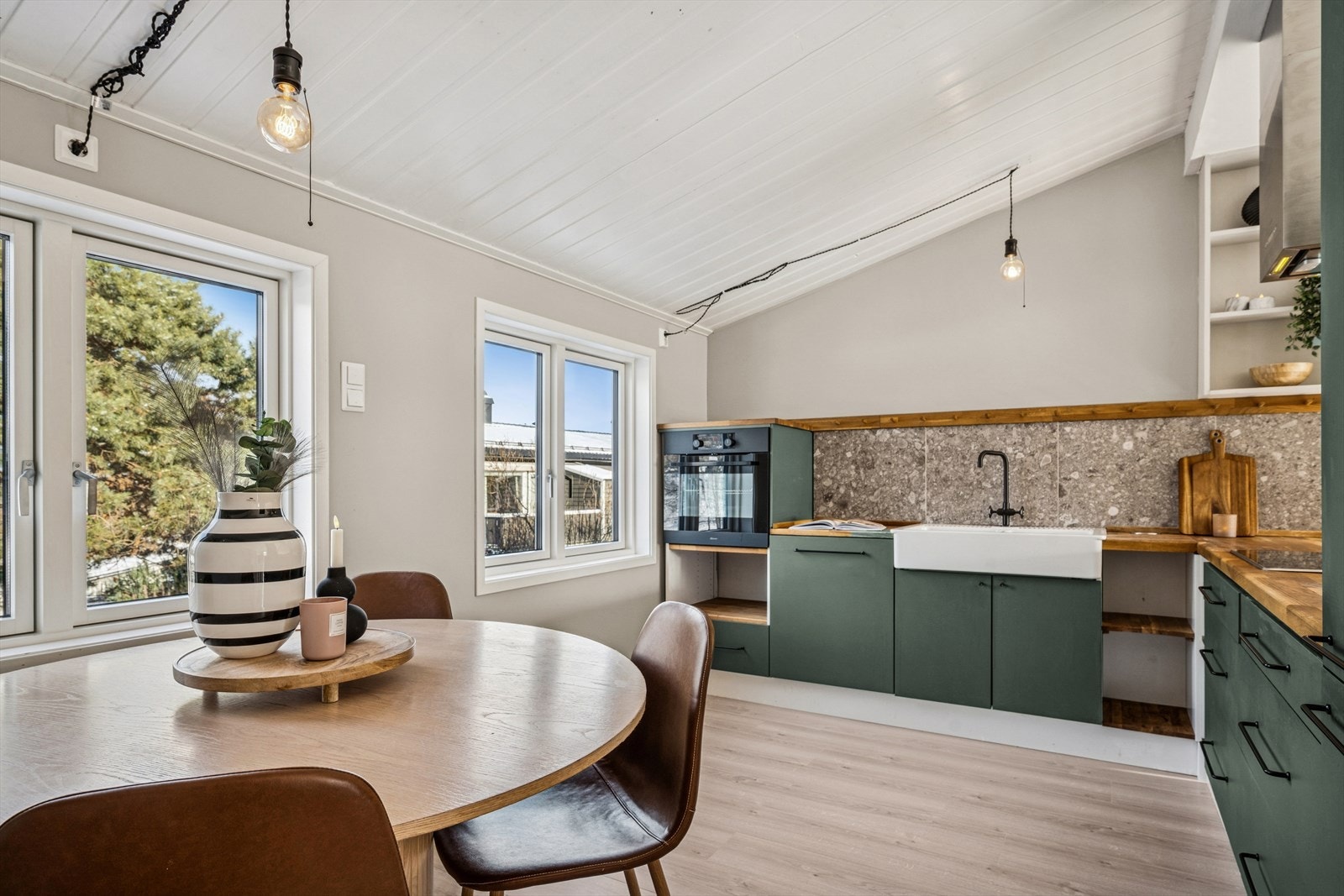 Kjøkkeninnredning med glatte fronter og heltre benkeplate. Fliser over benk og nedfelt porselenskum. Galleribilde