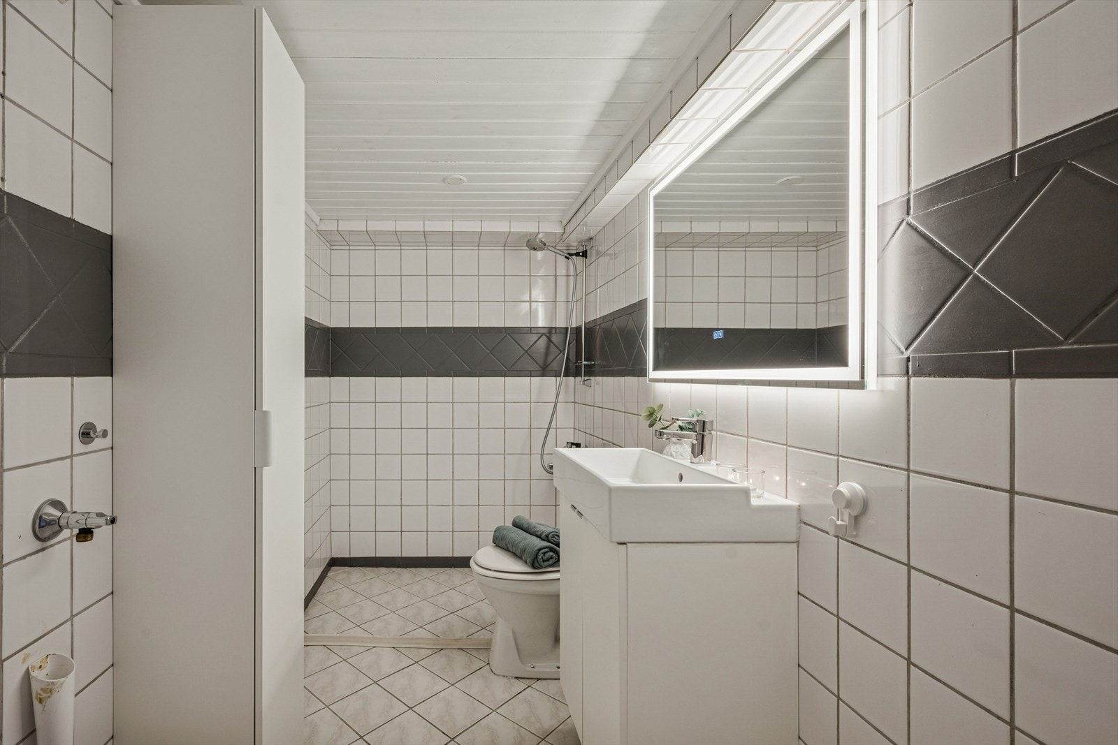 Bad med flislagte overflater og dusjløsning. Eldre standard og konstruksjon. Galleribilde