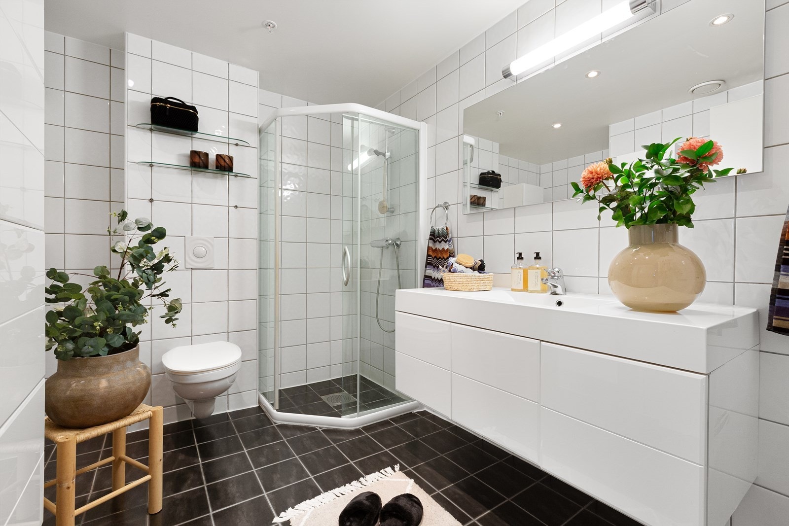 Helfliset baderom innredet med vegghengt toalett, servant, dusj og opplegg for vaskemaskin. Galleribilde