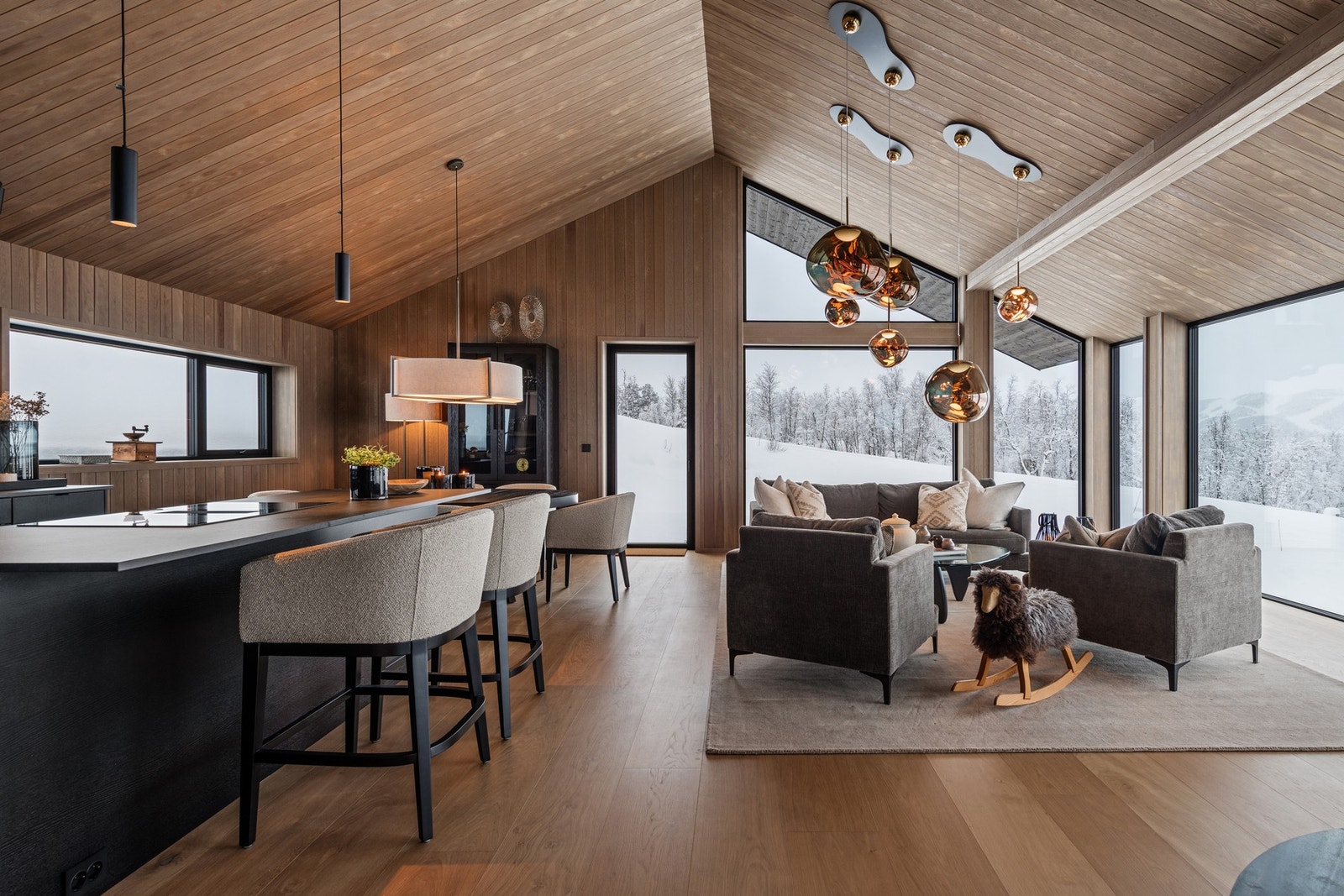 Den åpne stuen byr på utsikt mot snødekte fjell og vinterlandskap Galleribilde