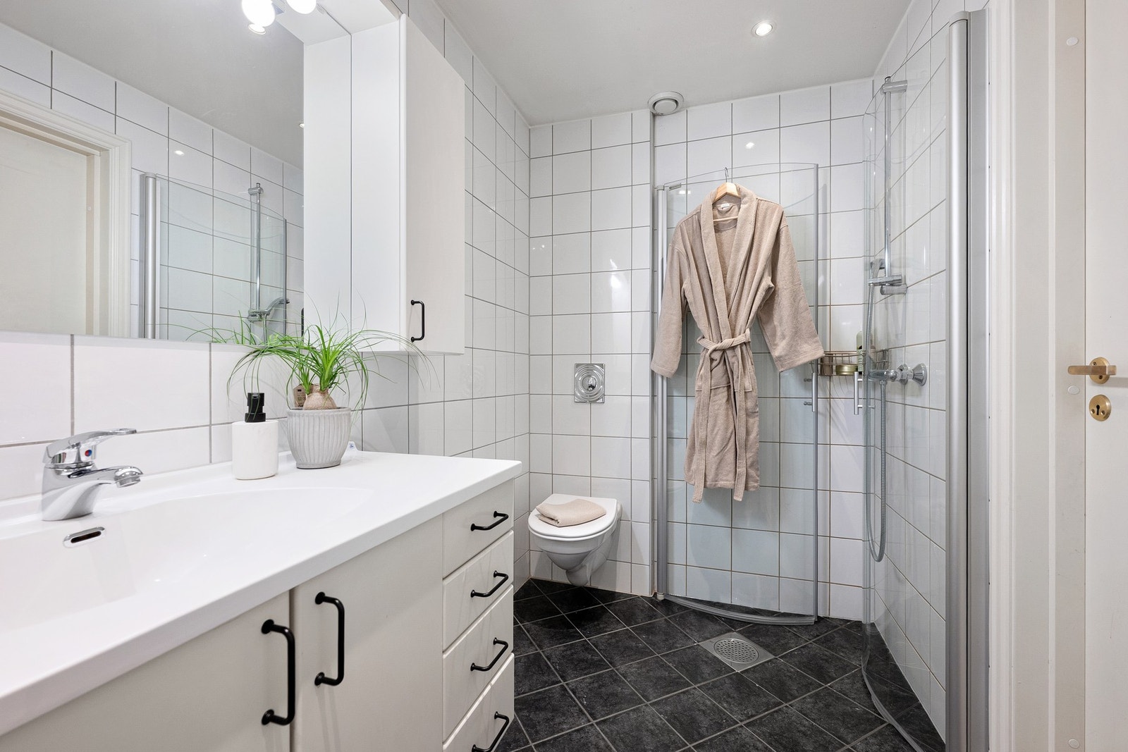 flislagte overflater og funksjonell innredning med heldekkende servant og oppbevaringsplass i servantskap. Samt varmekabler i gulvet. Galleribilde