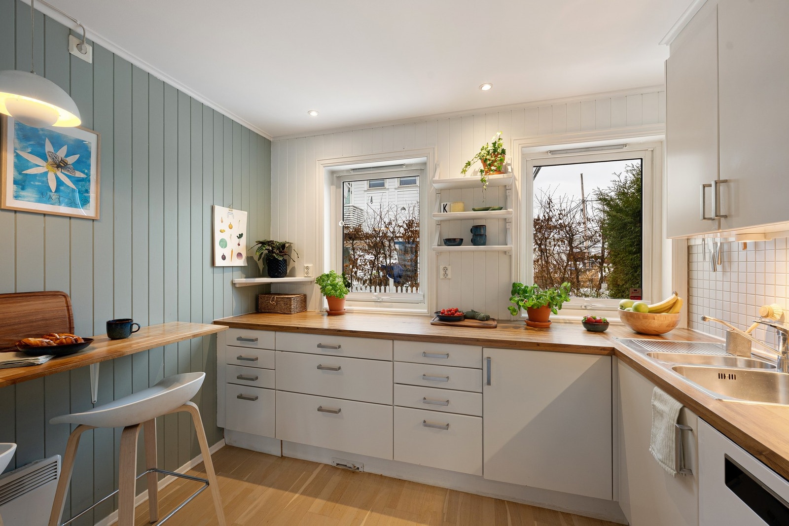 Utsyn fra kjøkkenvinduet mot grønt uteområde, med blåbærbusker utenfor - en fin detalj som gir et hyggelig preg. Galleribilde