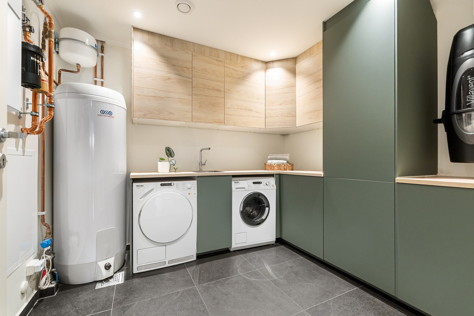 Det praktiske vaskerommet er velutstyrt, med flislagt gulv med vannbåren varme, gode oppbevaringsløsninger og opplegg for vaskemaskin og tørketrommel. Galleribilde