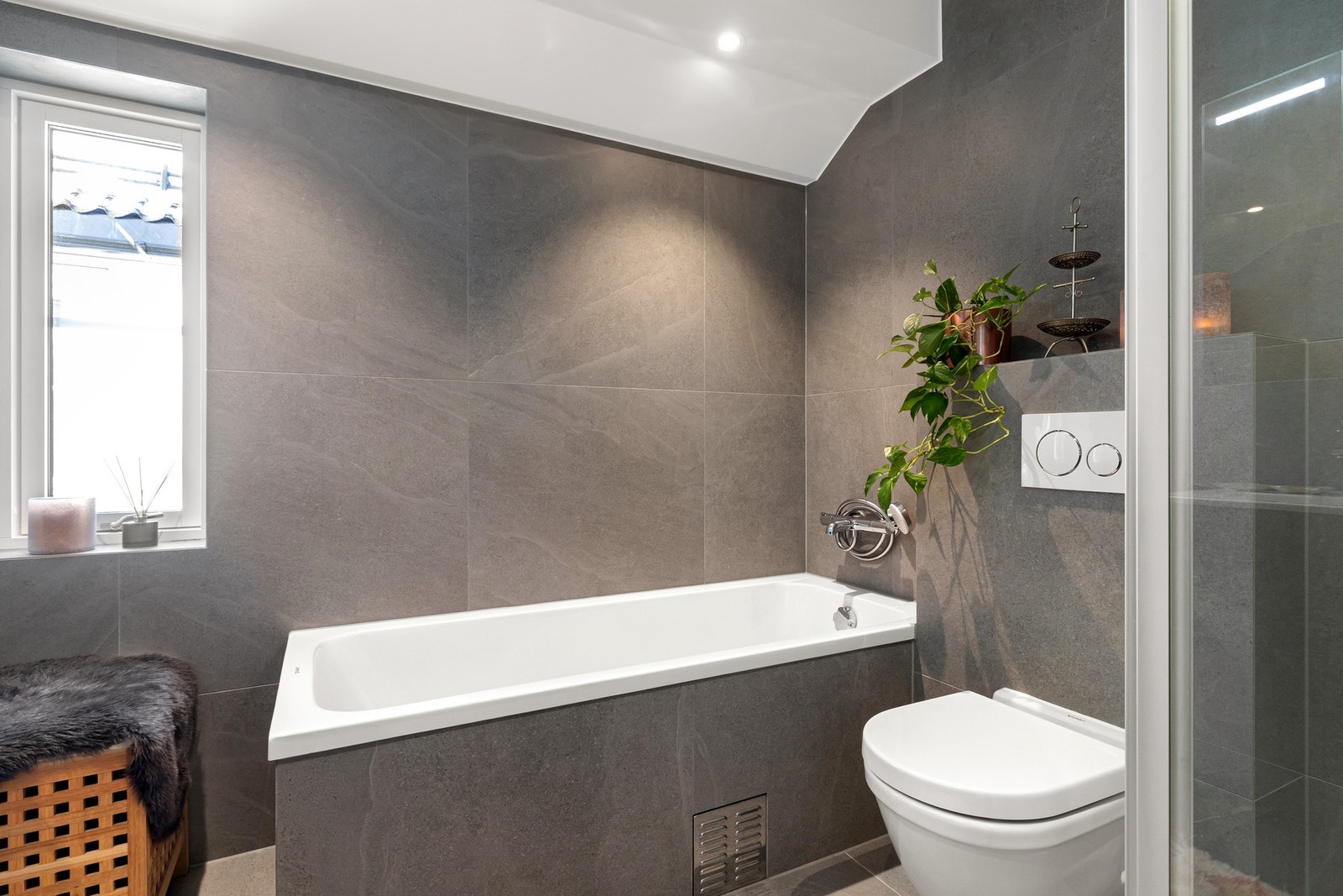 Badet er innredet med en dusjnisje, innfliset badekar, toalett og dobbel servant med vegghengt speilskap over. Galleribilde