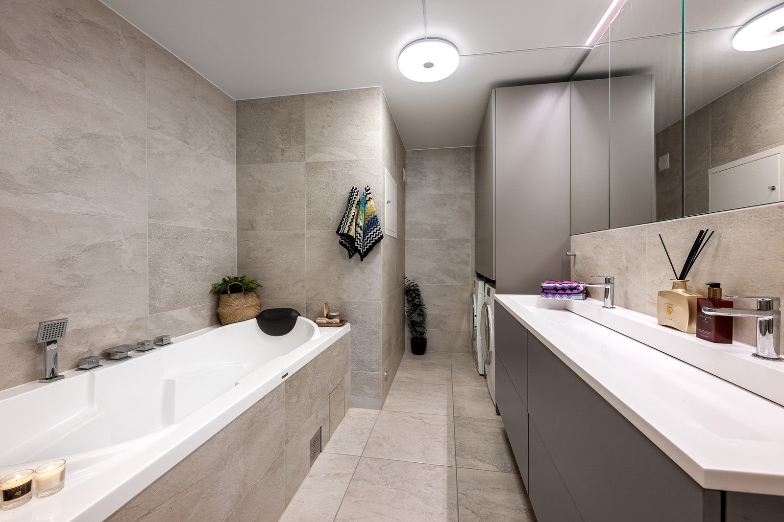 Gjennomført løsning med dobbel servant, samt opplegg for vaskemaskin og tørketrommel med tilhørende skapinnredning. Galleribilde