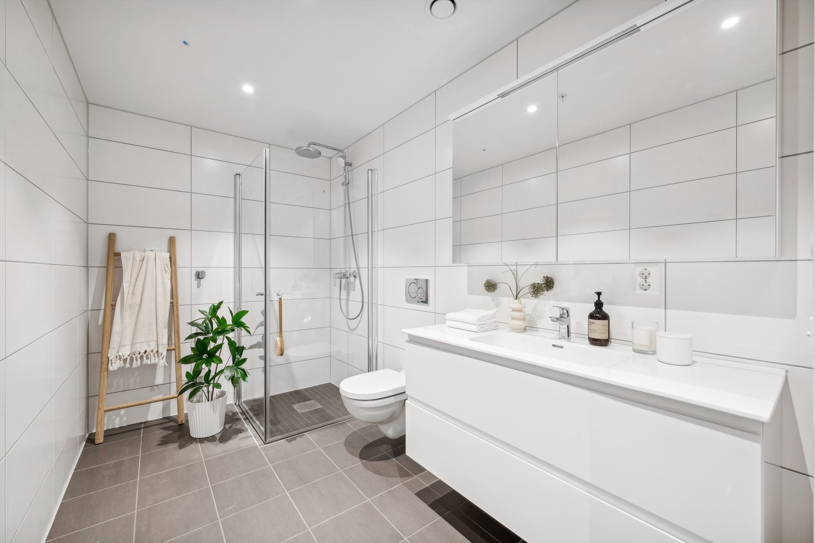 Baderommet har stilren innredning fra Foss, med brede skuffer og heldekkende servant. Speilskap med lysplate over baderomsmøbel, vegghengt toalett fra Villeroy og Boch og dusjnisje med nedsenket sone Galleribilde