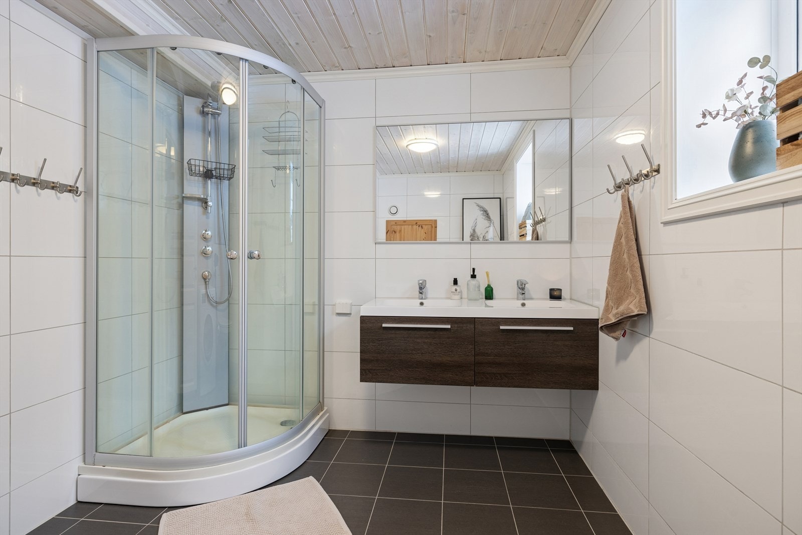 Badet er utstyrt med servantinnredning med glatte fronter, helstøpt dobbel servant, oppbevaring i skuffeseksjon og speil Galleribilde