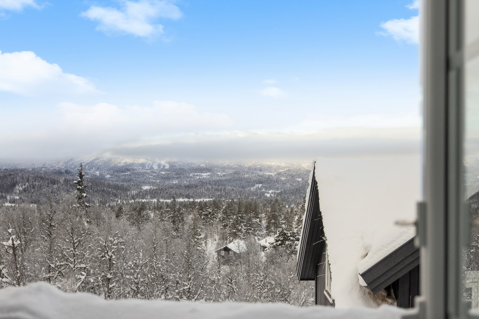 Fra loftsetasjen er det nydelig utsikt over ruvende fjelltopper og omkringliggende hytter Galleribilde