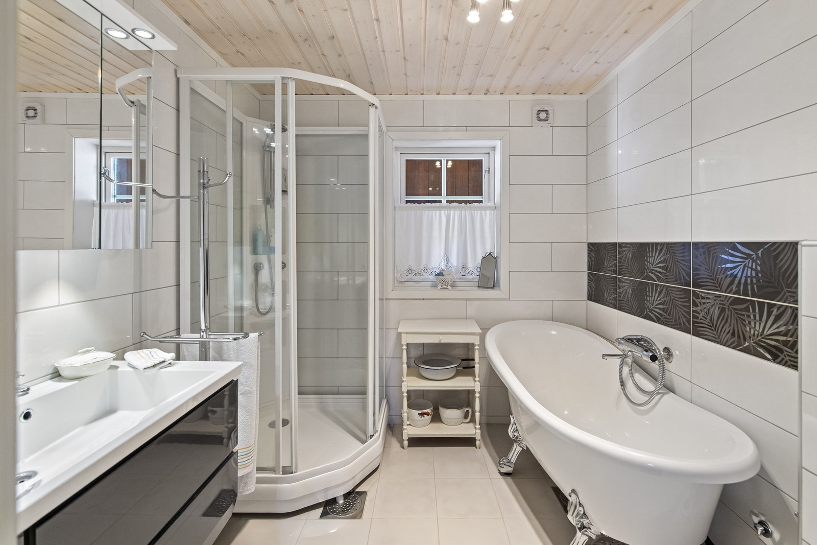 Badet er innredet med badekar, dusjkabinett, vegghengt toalett og servant i innredning Galleribilde