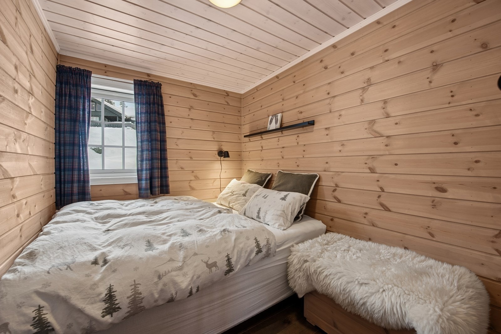 Soverom med dobbeltseng og tradisjonelle materialvalg som gir en lun atmosfære. Galleribilde