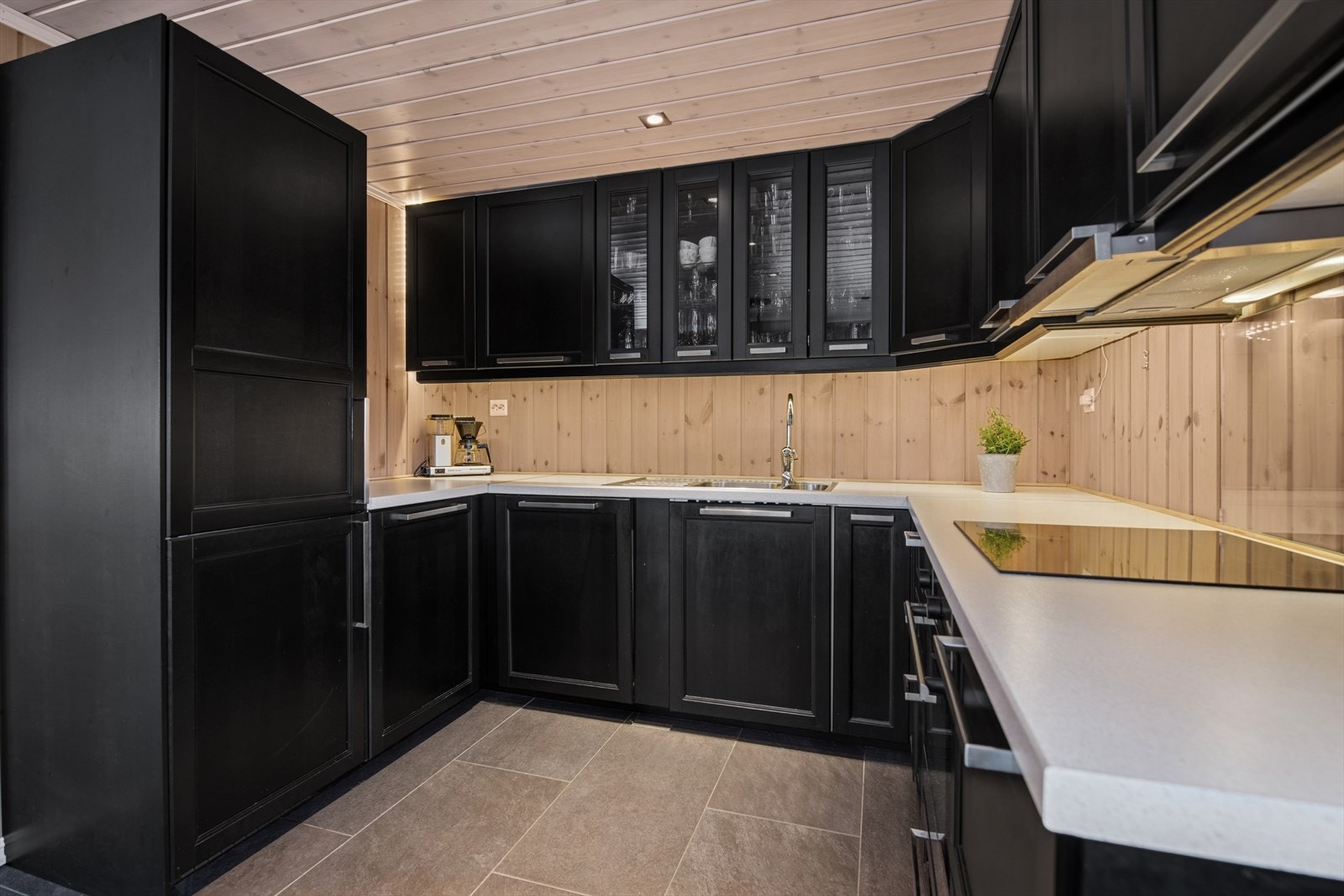 Kjøkkenet kombinerer sorte speilfronter, vitrineskap og integrerte hvitevarer - en helhetlig og funksjonell løsning som både imponerer og innbyr til matlaging. Galleribilde