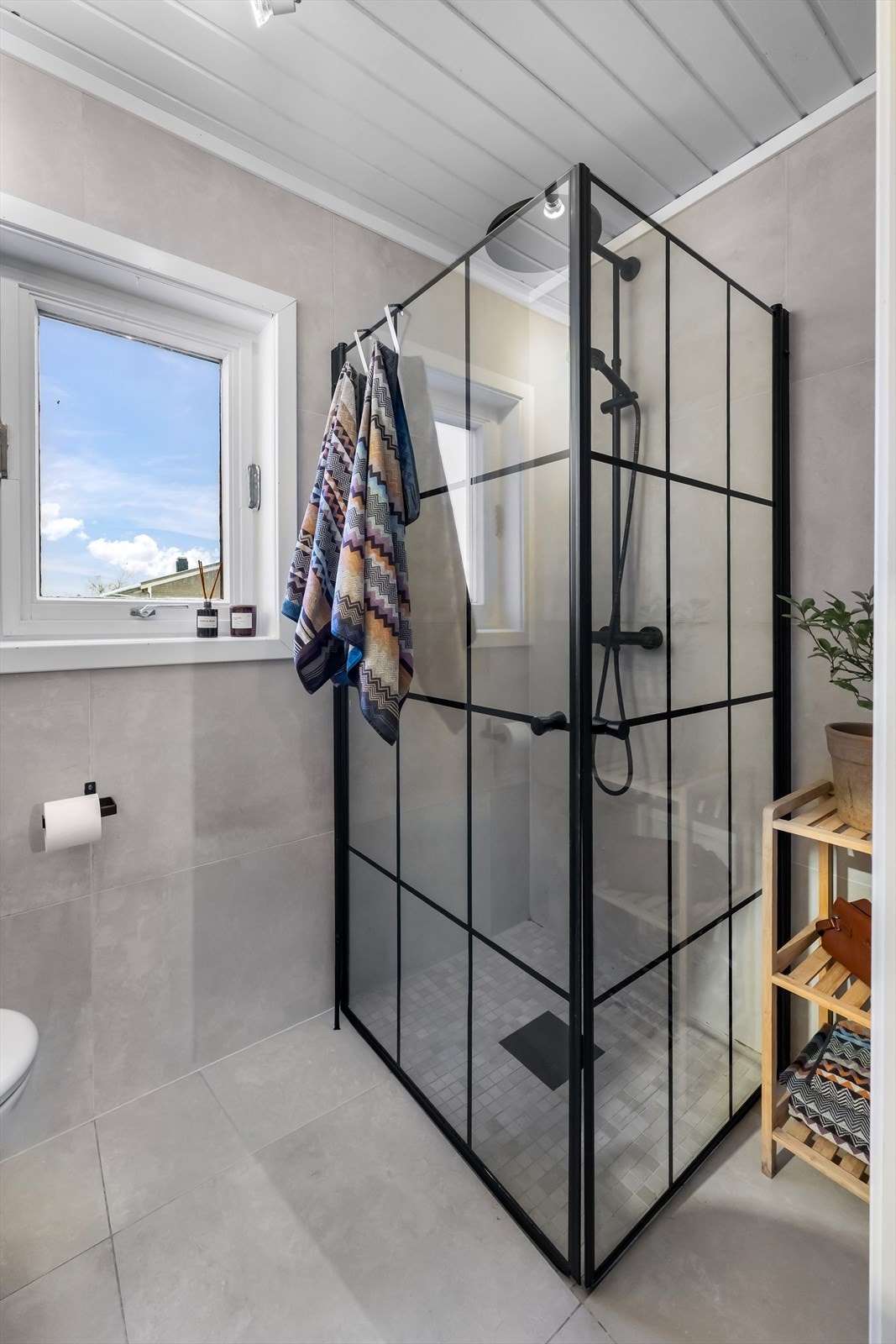 Rommet er innredet med en baderomsinnredning med servant/bollevask og speil, et veggmontert toalett og et dusjhjørne med rette, innsvingbare glassdører. Galleribilde