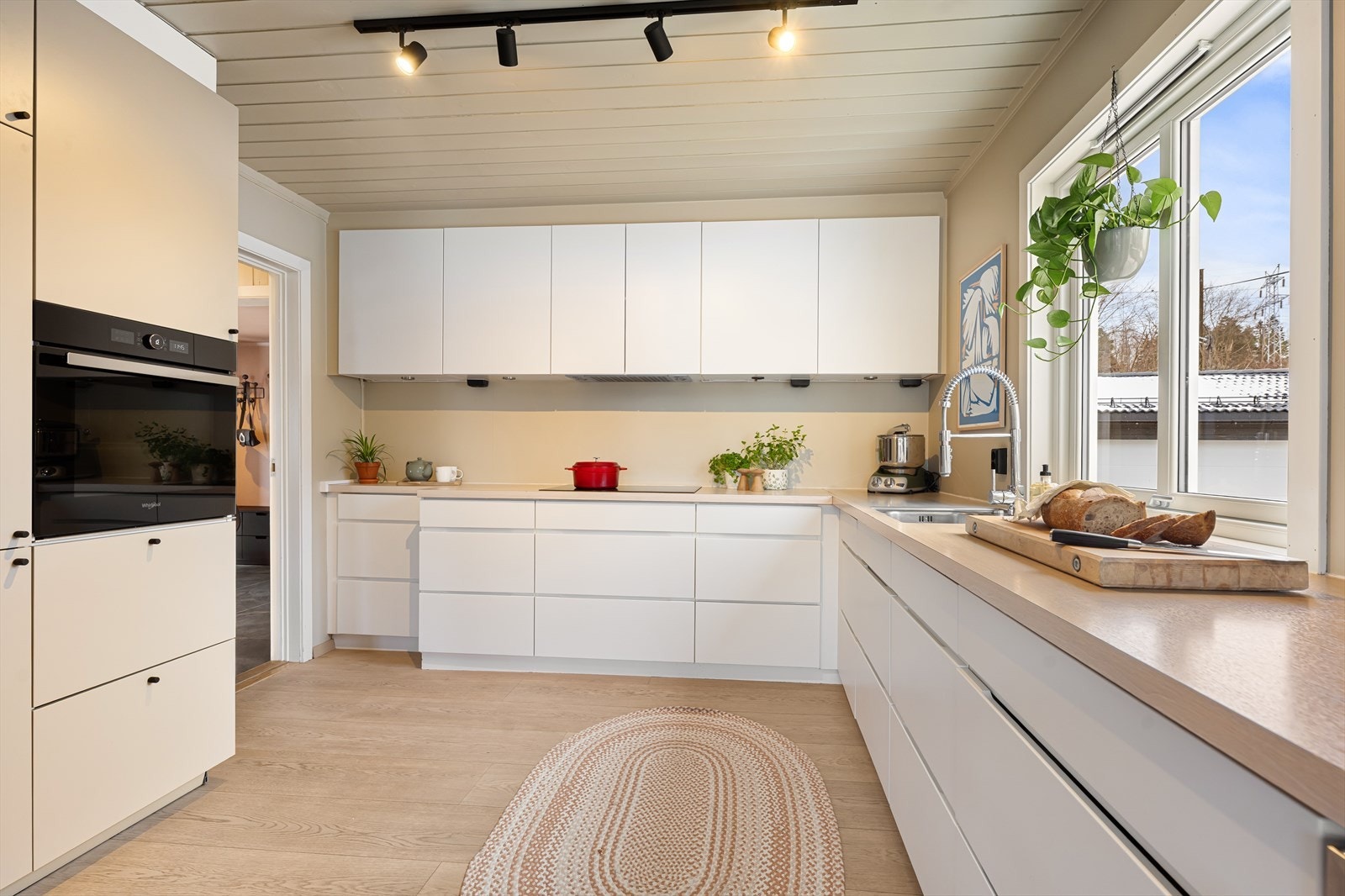 Stilrent kjøkken fra 2010 med slette hvite fronter og nedfelt vaskekum i laminat benkeplate. Galleribilde