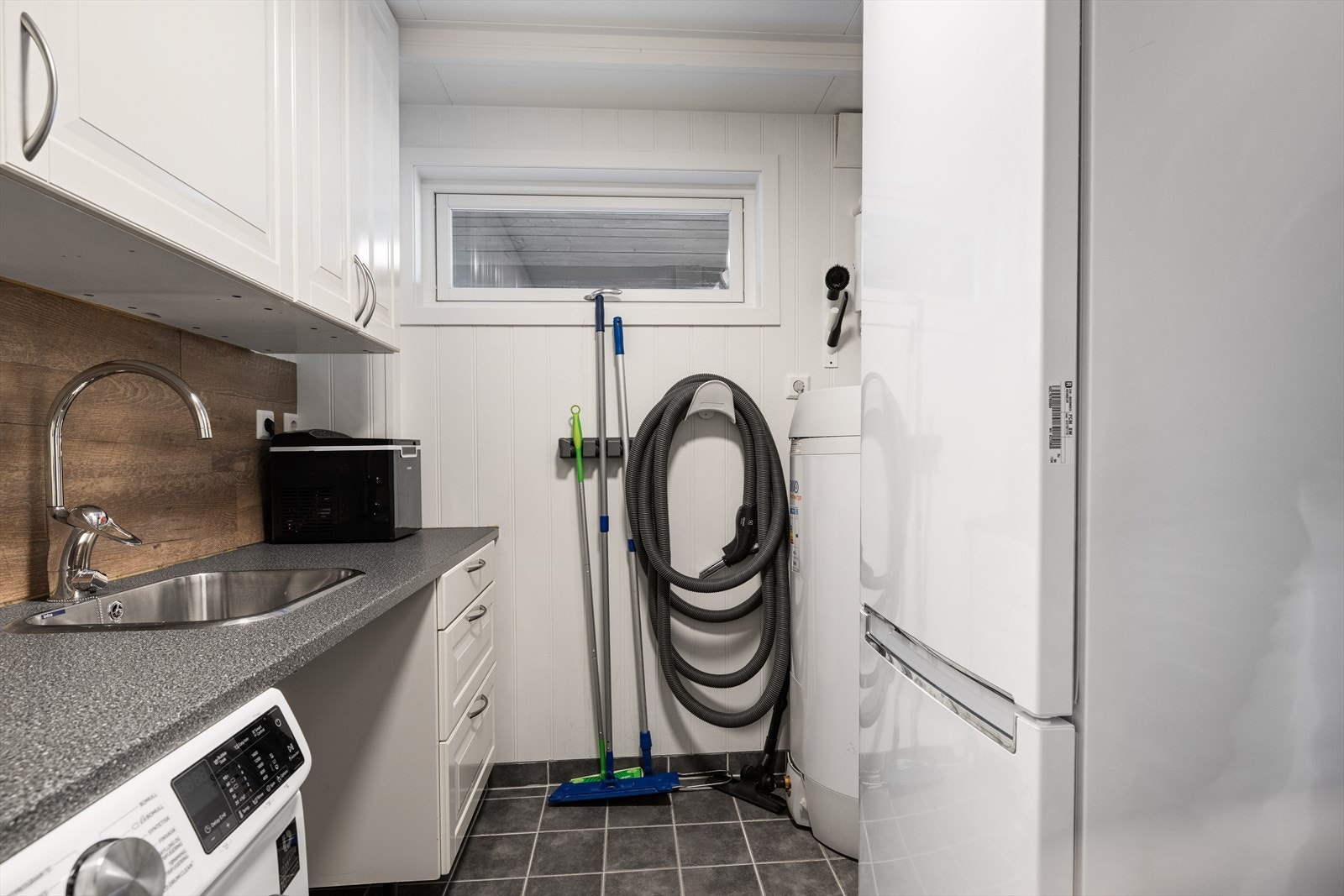 Vaskerommet har flislagte gulvflater, nyere varmtvannstank og utslagsvask, i tillegg til plass til vaskemaskin og tørketrommel. Galleribilde