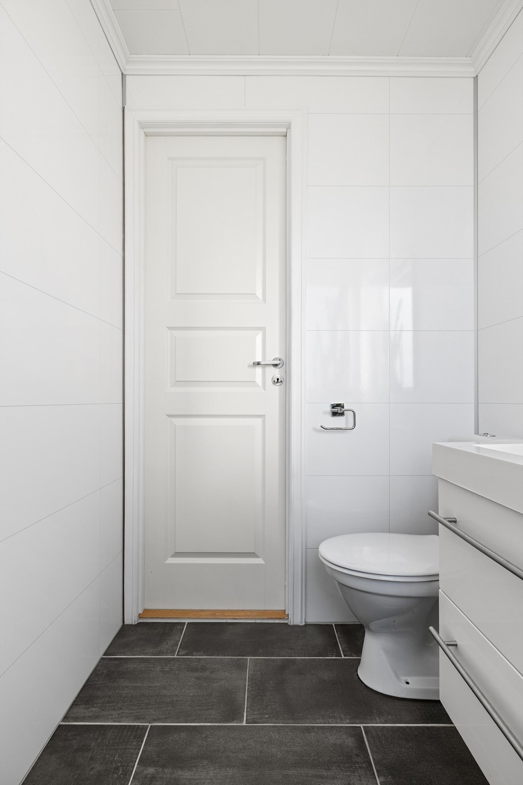 Toalettrommet har også flislagte gulvflater og baderomsplater på veggene. Wc og servant med innredning. Galleribilde