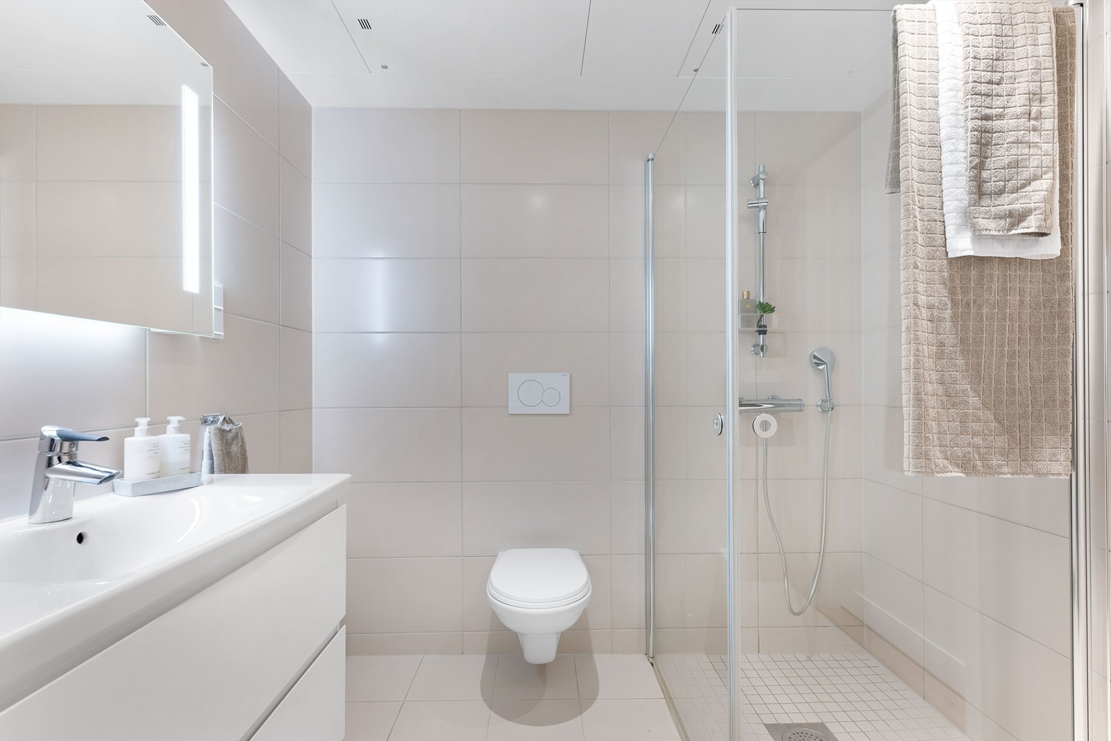 Badet er utstyrt med dusjhjørne, vegghengt WC, moderne baderomsmøbler og opplegg for vaskemaskin. Galleribilde