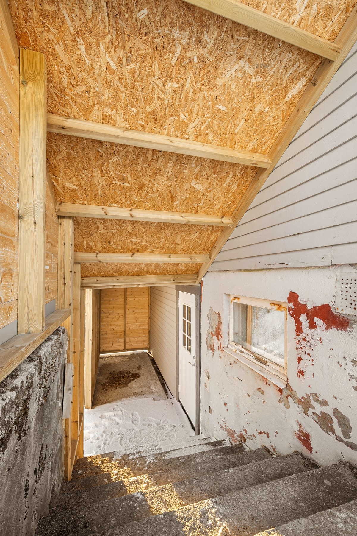 Overbygd inngangsparti til kjeller (bygd 2024) gir god lagring for ved og annet Galleribilde
