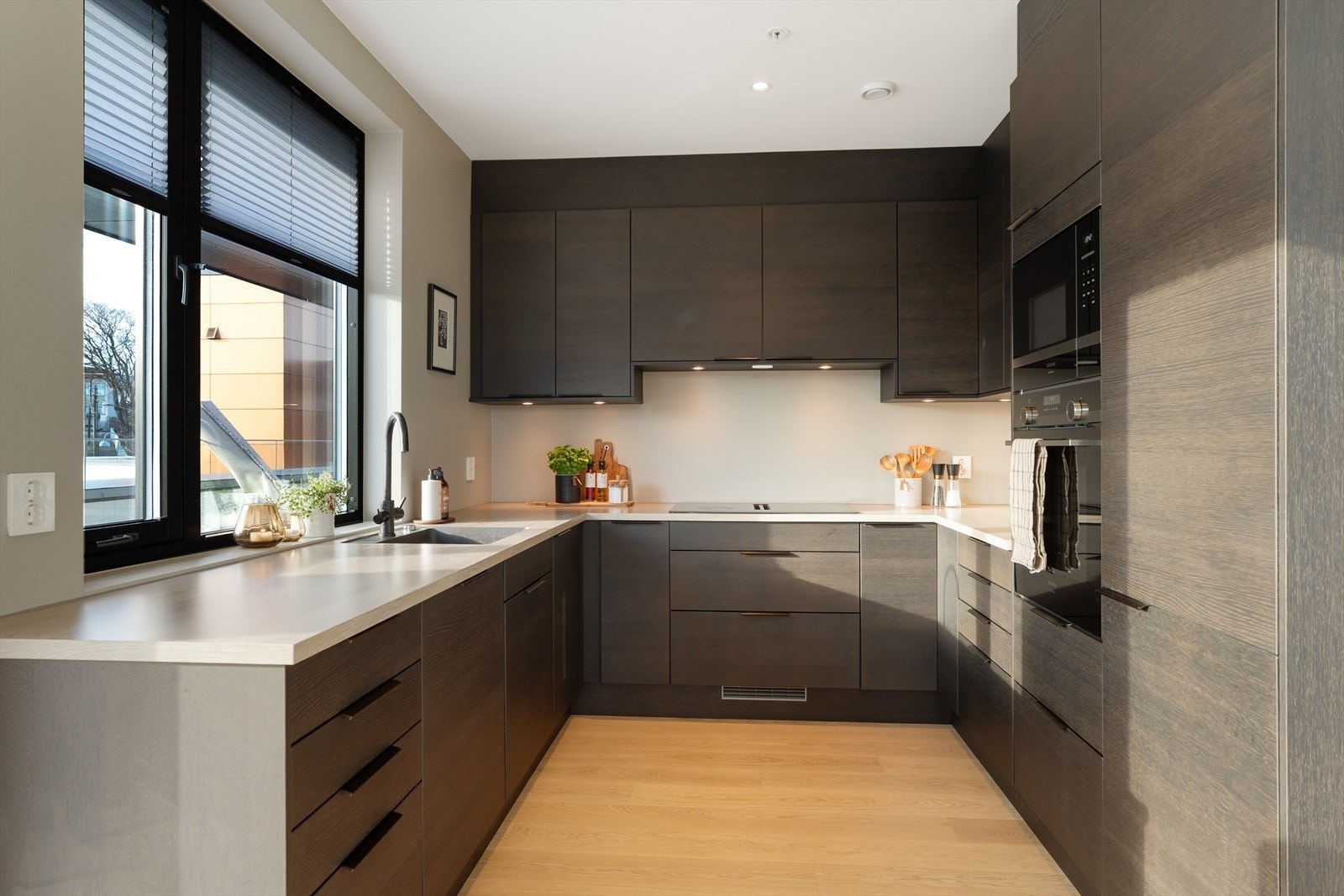 Kjøkkenet er innredet med slette fronter og benkeplate i laminat - alle hvitevarer er integrert for et helhetlig og stilrent uttrykk Galleribilde