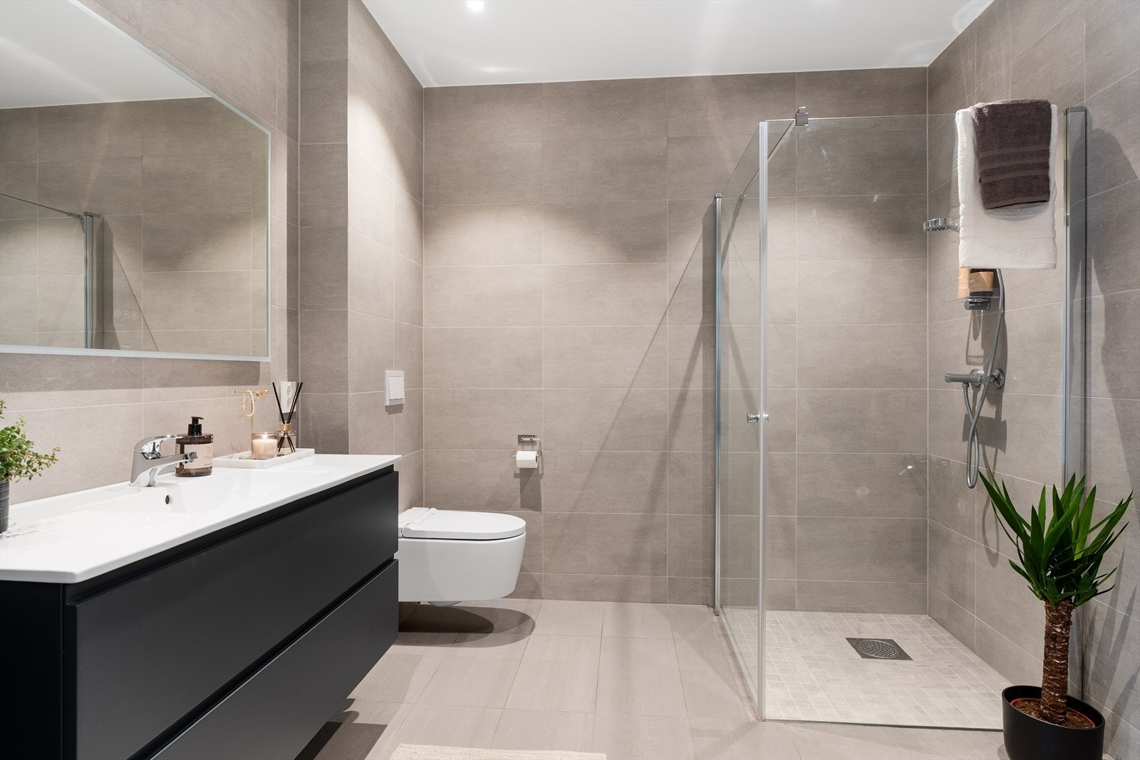 Leiligheten har et delikat og moderne bad med fliser på både vegg- og gulvoverflater, samt slette plater i himlingen - gulvet er utstyrt med vannbåren gulvvarme Galleribilde