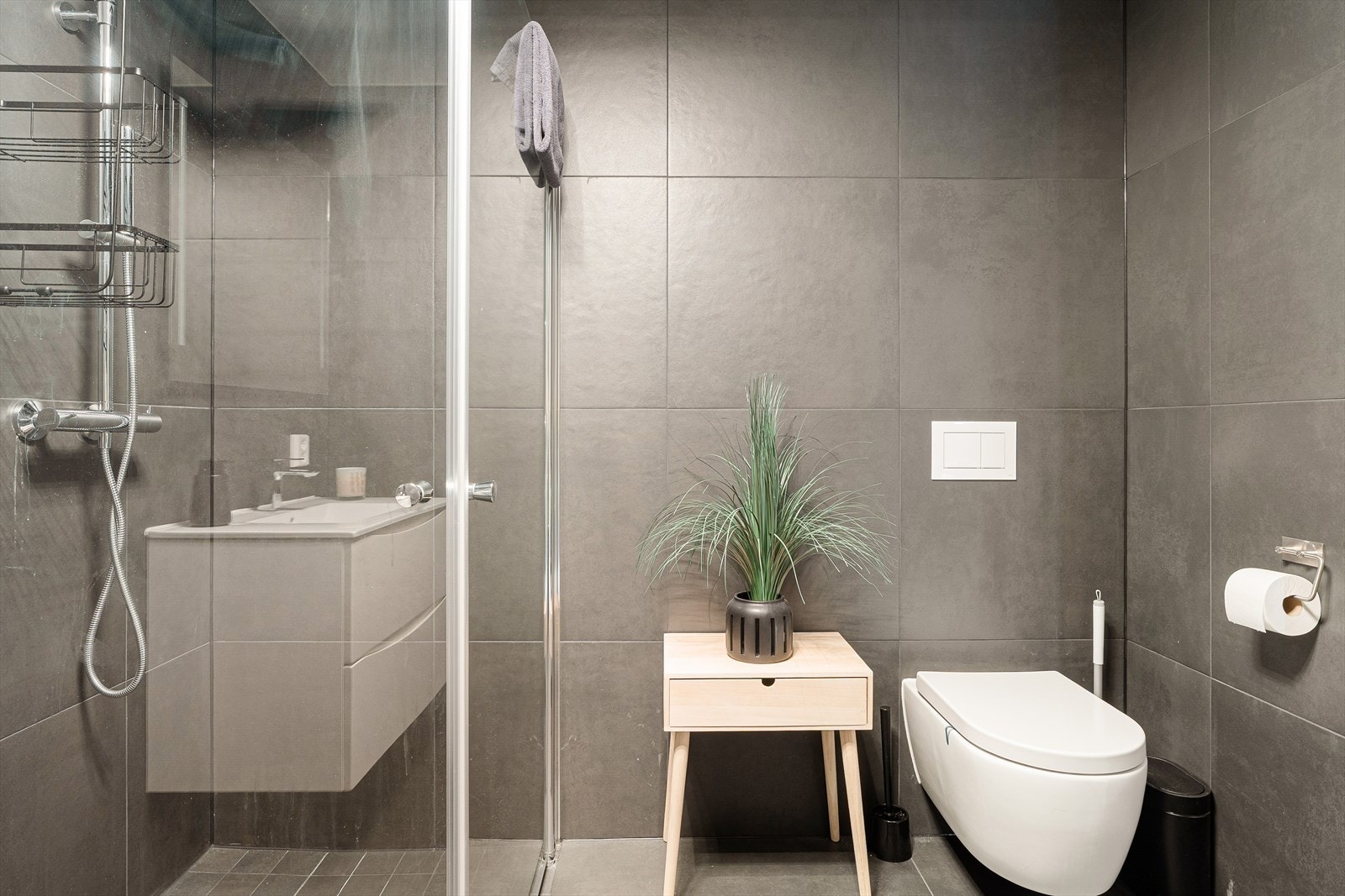 Badet er innredet med vegghengt toalett, dusjhjørne og innredning med heldekkende servant. Det er elektrisk varmekabel i gulvet. Galleribilde