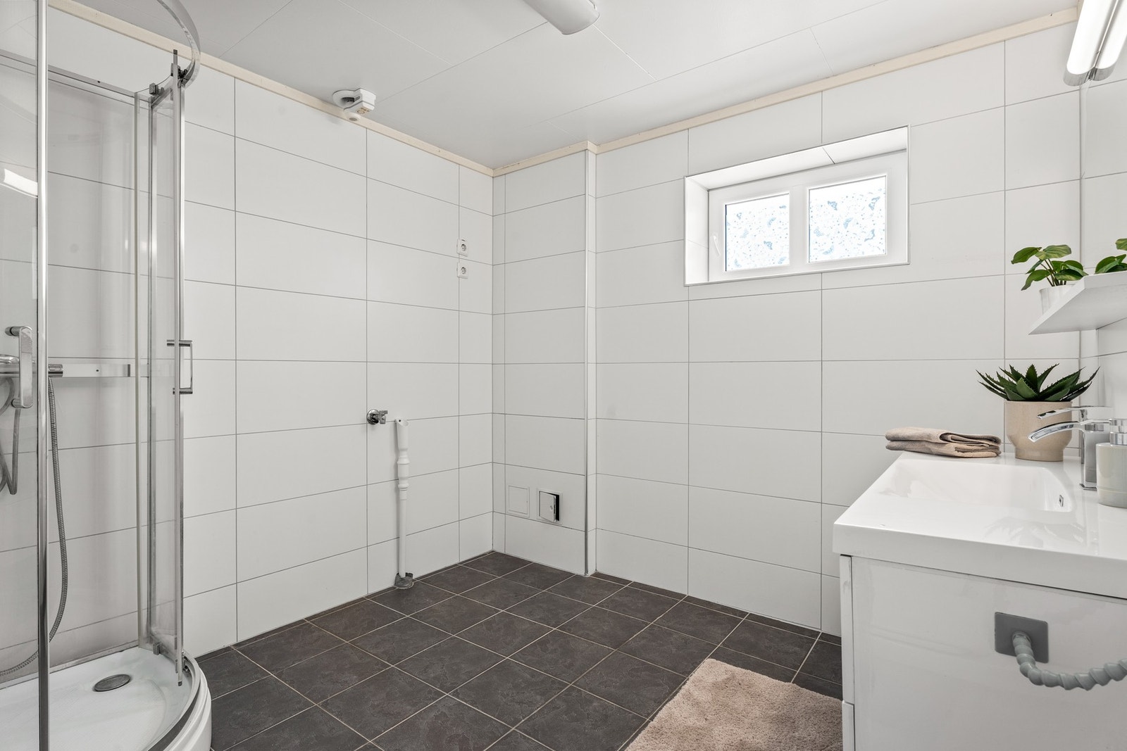 Stort flislagt baderom med opplegg for vaskemaskin Galleribilde