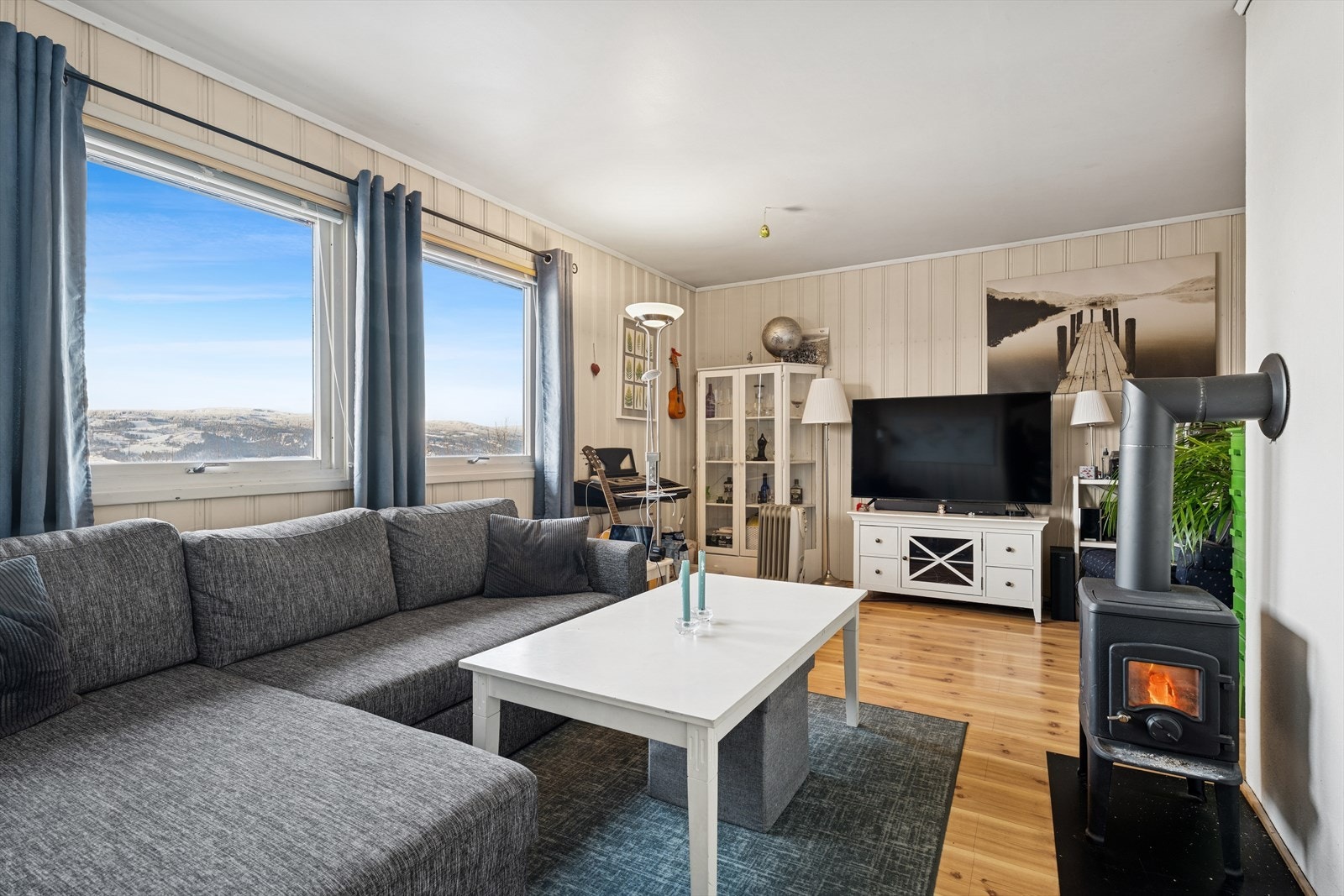 Stue og kjøkken ligger i åpen løsning. Også her har man store vindusflater som gir godt med naturlig lys og flott utsikt. Stuen er også utstyrt med en vedovn som gir god varme. Galleribilde