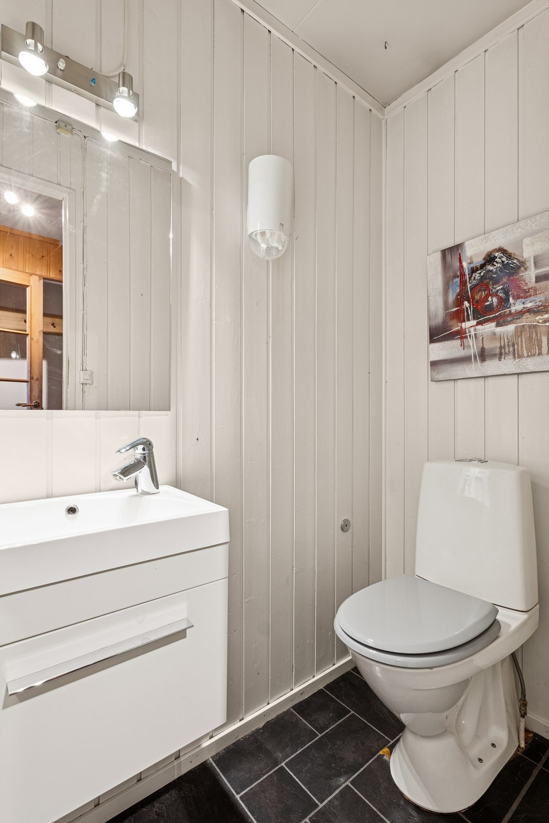 I første etasje finner man også et toalettrom som er innredet med grå laminat på gulv og malt panel på vegg. Rommet er ellers utstyrt med toalett og baderomsinnredning med servant. Galleribilde