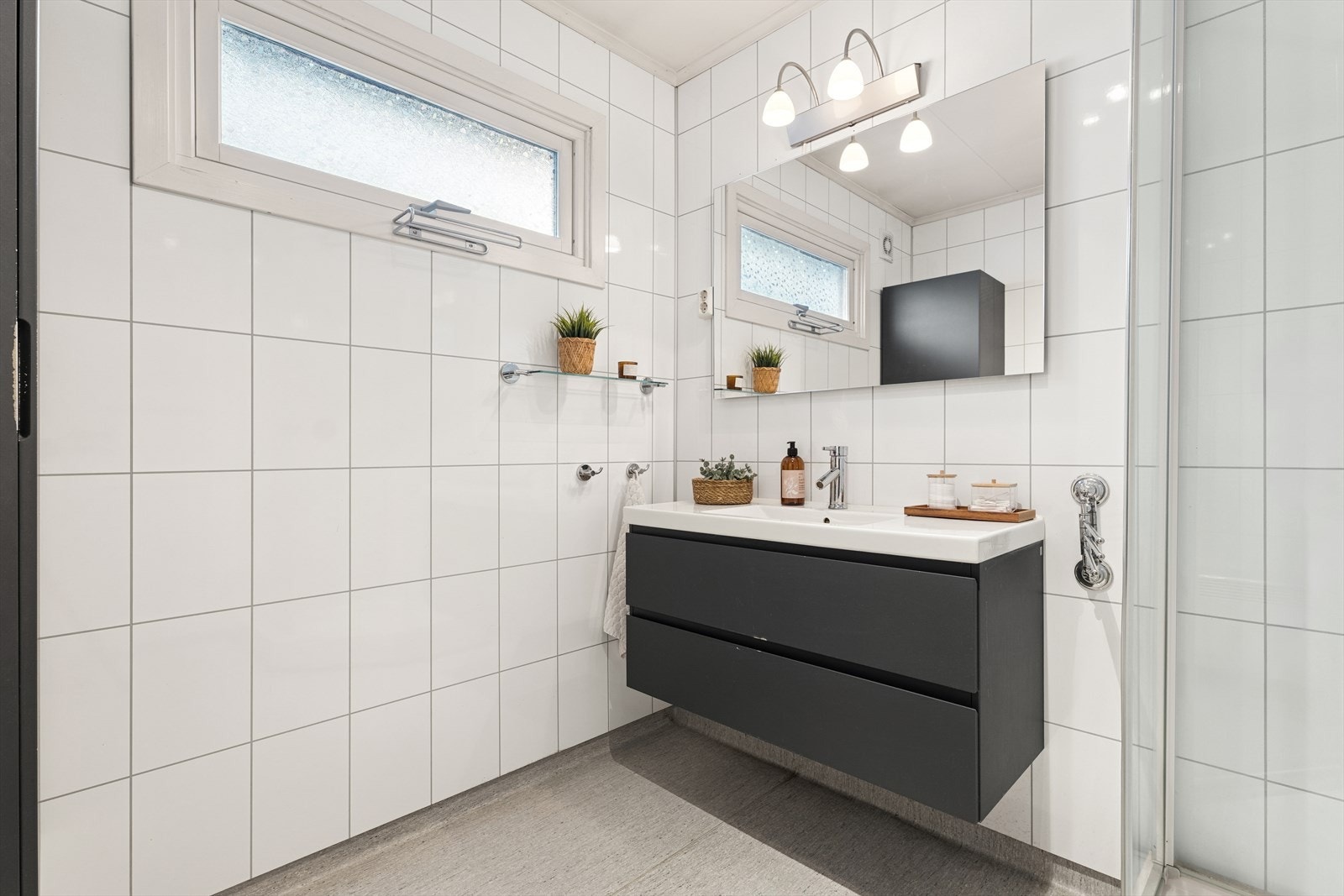 Baderommet ble pusset opp i 2011 og er tidløst innredet med grått belegg på gulv og hvite baderomsplater på vegg. Galleribilde