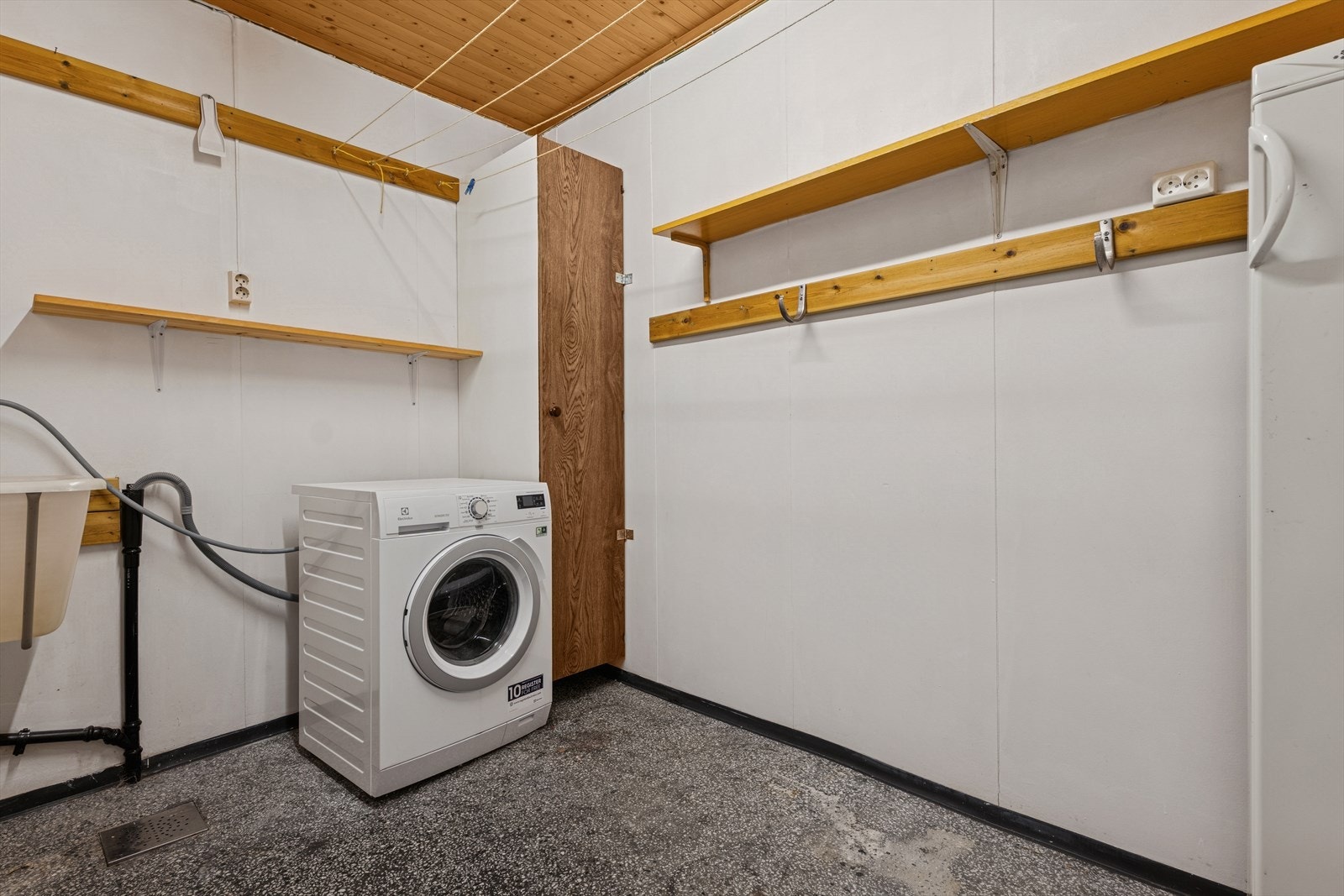 Videre finner man et vaskerom som er enkelt innredet med betonggulv og malte plater på vegg. Rommet er ellers utstyrt med utslagsvask og opplegg til vaskemaskin. Her kan man med litt kjærlighet skape seg et flott og praktisk vaskerom med god lagringsplass Galleribilde