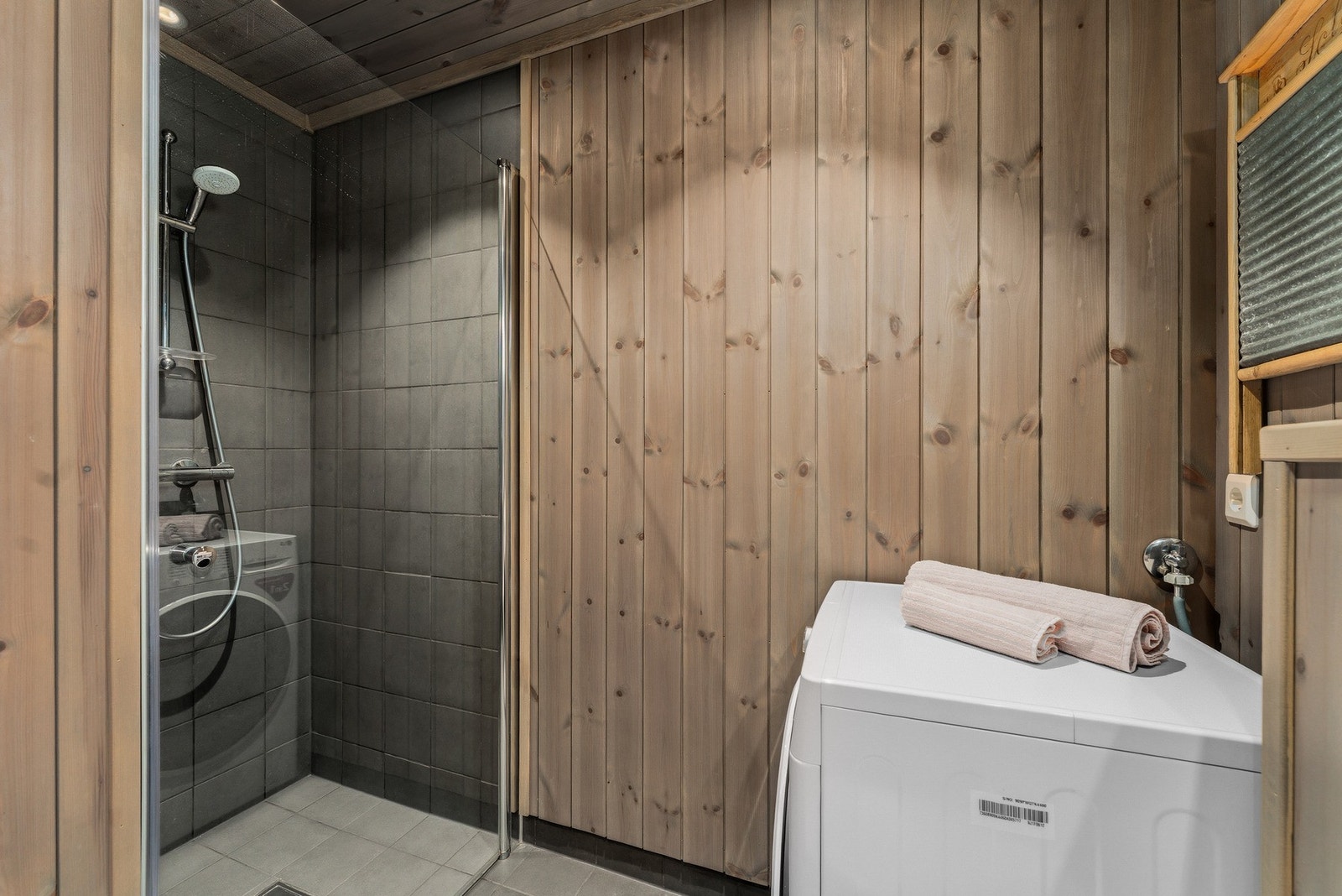 Badet er innredet med nedfelt servant, veggmontert toalett, dusjnisje og opplegg for vaskemaskin. Galleribilde