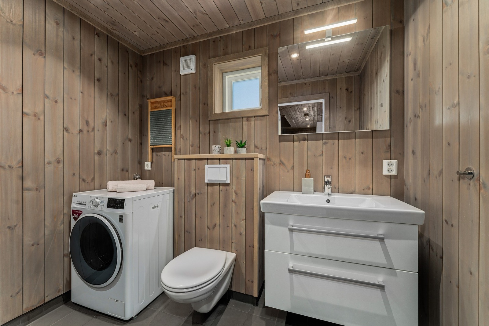 Badet er delikat utført med fliser i dusjsonen og panel på øvrige vegger, kombinert med trepanel i tak og flislagt gulv med elektriske varmekabler. Galleribilde