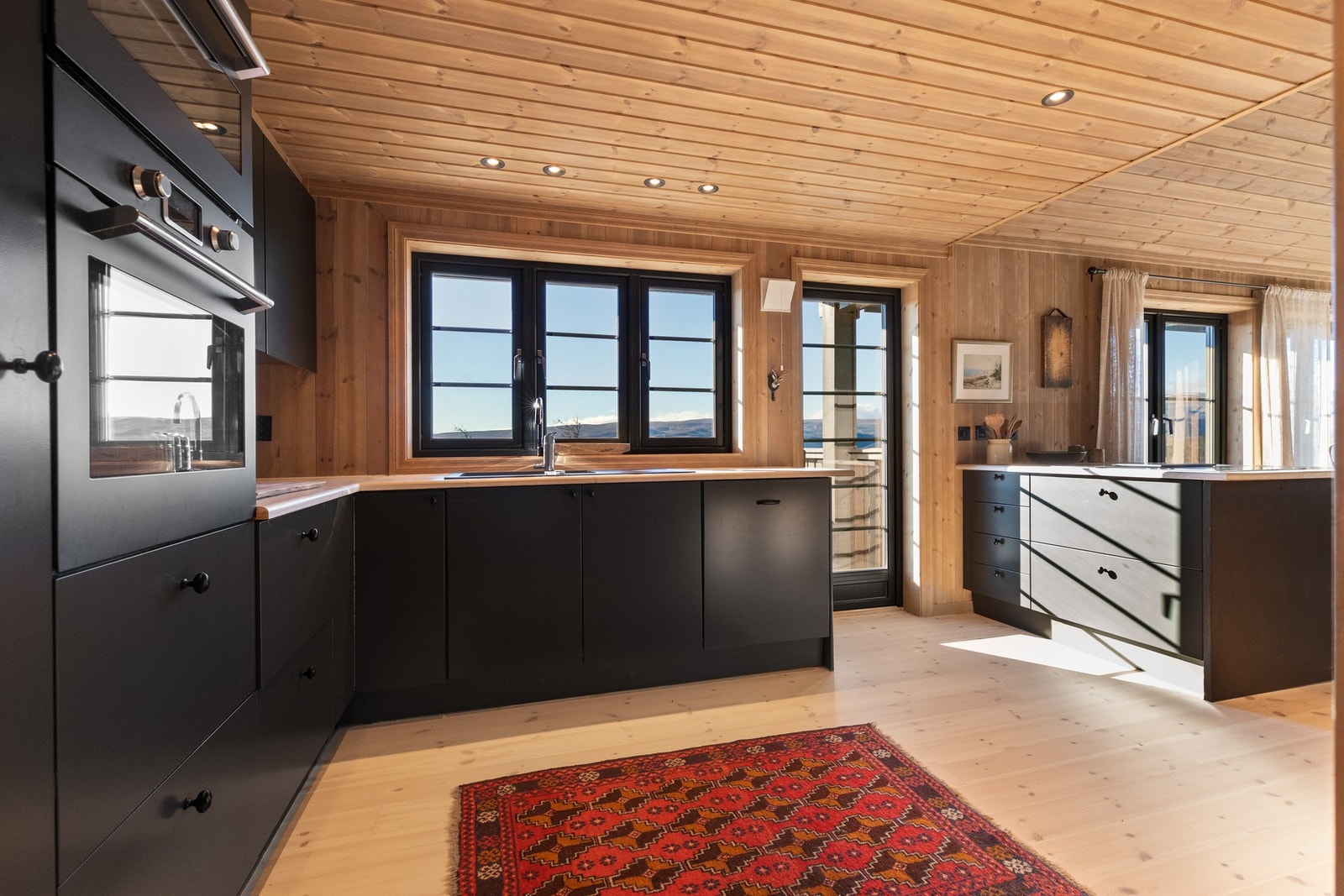 Kjøkkeninnredning med god skapplass. Glatte fronter i fargen "dempet sort", benkeplate i heltre Galleribilde