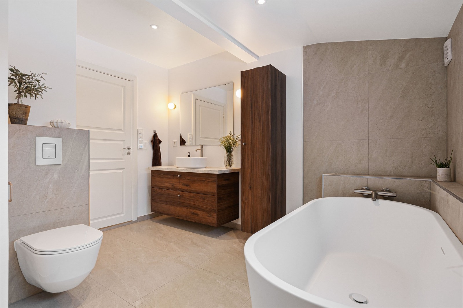 Stort, nytt og delikat flislagt bad med vegghengt toalett, badekar og stilig baderomsinnredning. Galleribilde