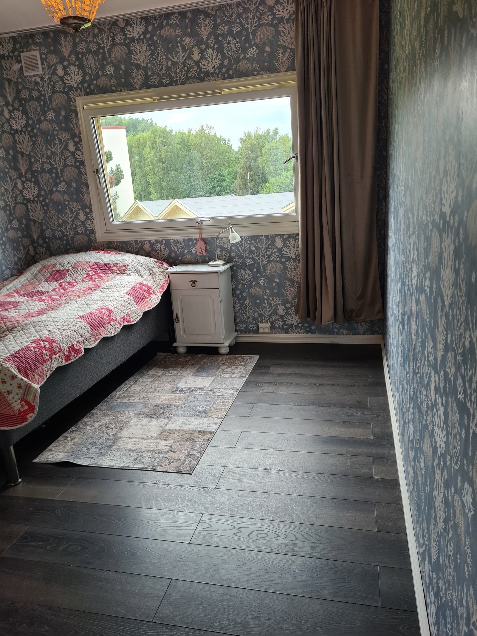 Soverom 1 med lys blå mønstret tapet, garderobeskap og stort vindu. Galleribilde