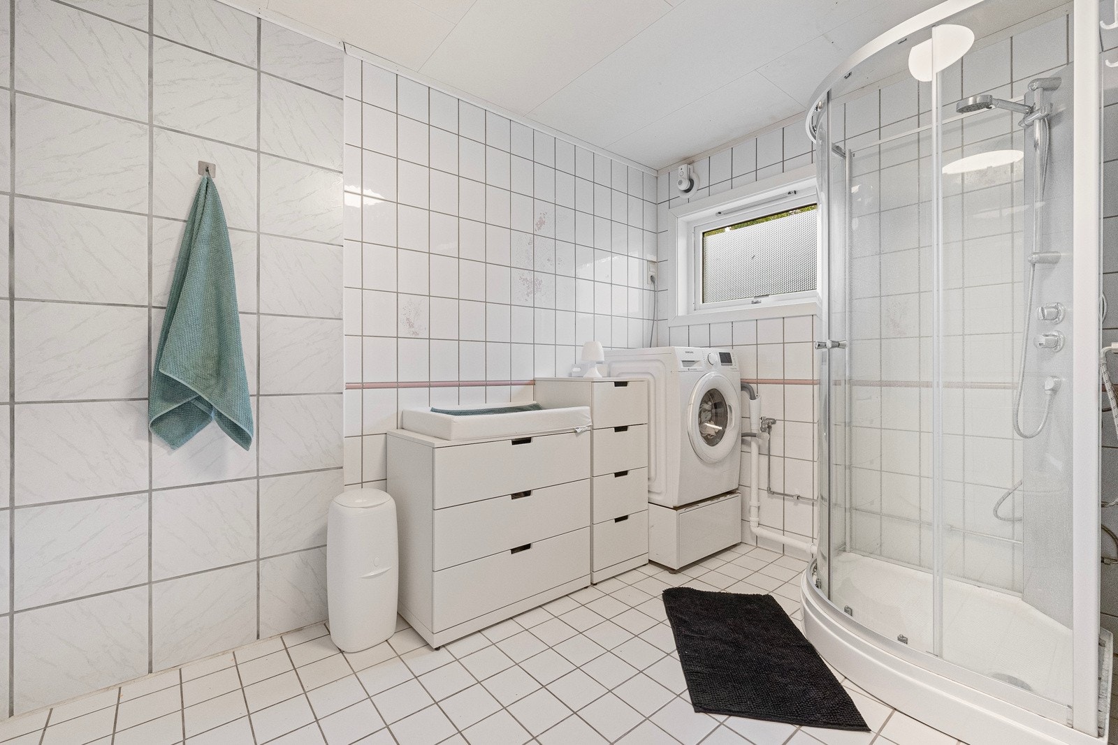 Badet er innredet med vaskemaskin, dusjkabinett, servant med skap og WC Galleribilde