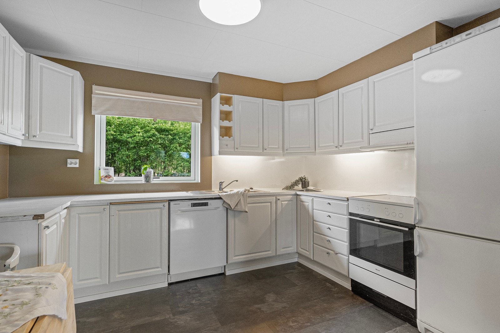 Kjøkkeninnredningen er fra 1993, med profilerte fronter, benkeplate med nedfelt vask, og plass til både oppvaskmaskin, komfyr og kjøleskap Galleribilde