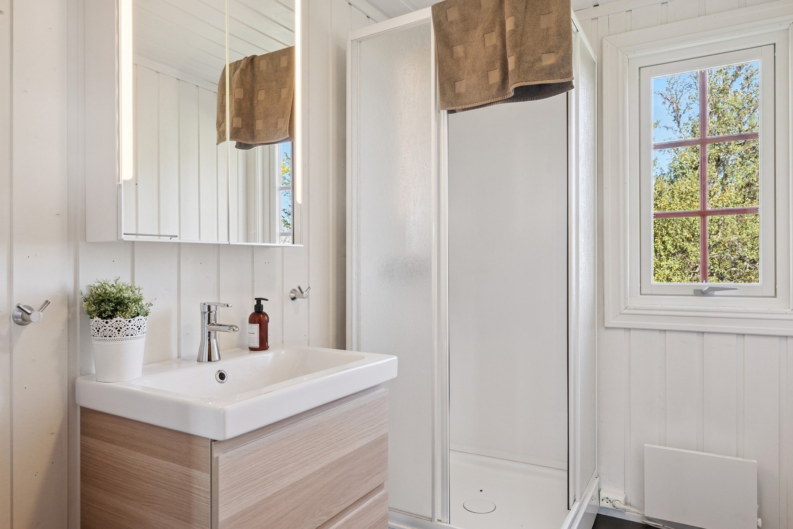 Badet har gulv av laminat og malt trepanel på vegg og himling. Galleribilde