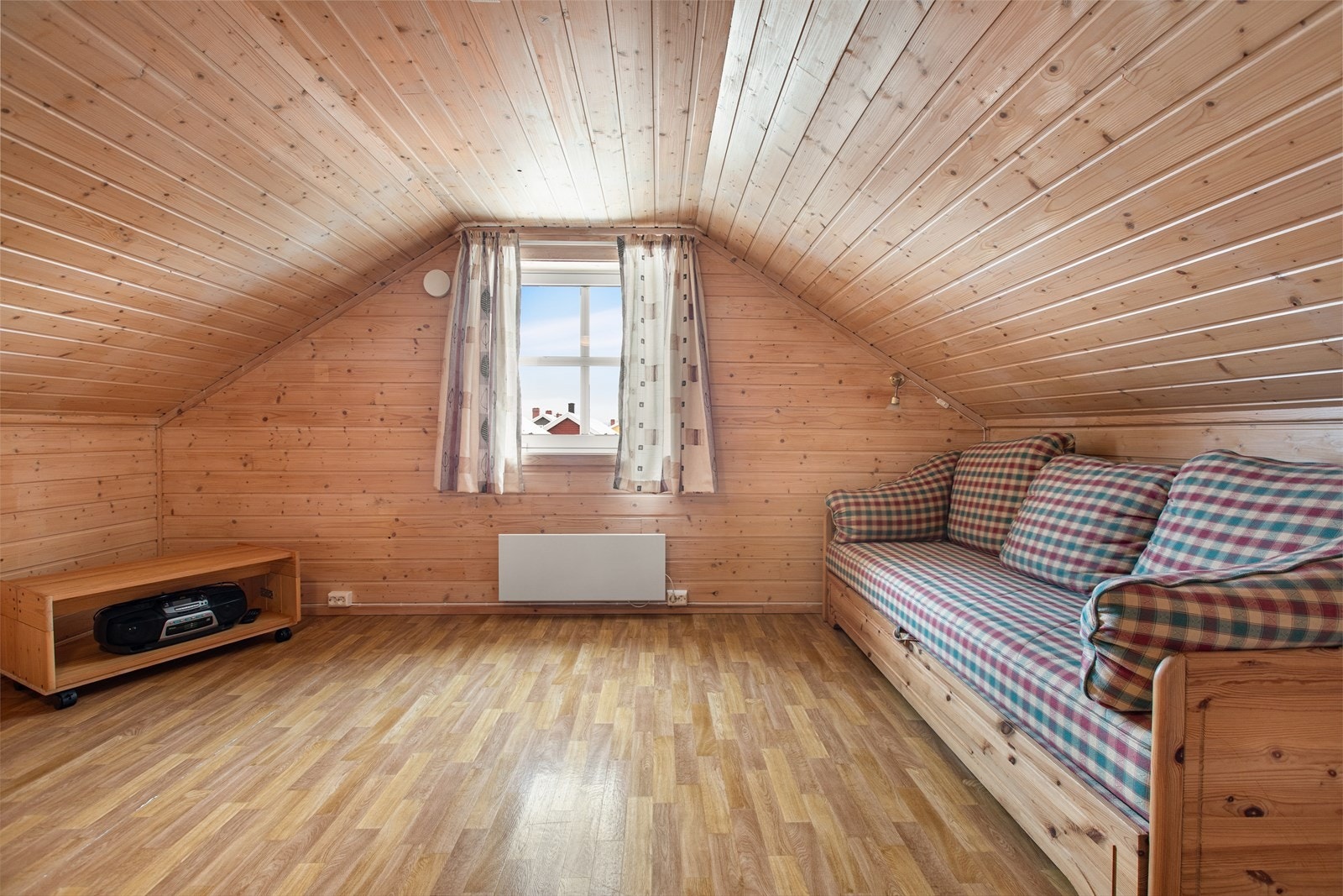 Loftstuen er utstyrt med panelte vegger og et vindu som gir naturlig lys. Galleribilde