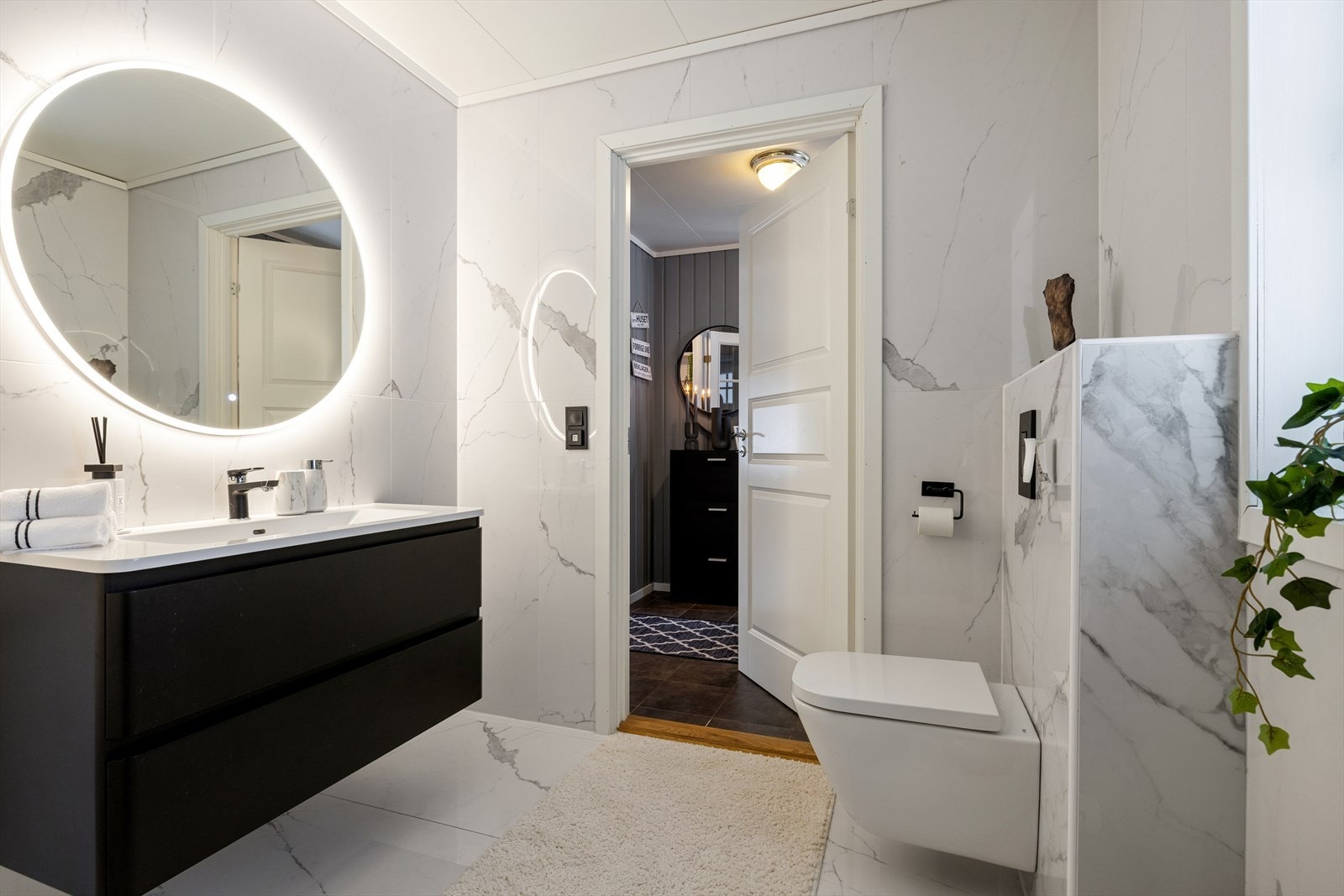 Moderne og stilren innredning med sort baderomsmøbel, lekker servant og stort LED-speil som gir et elegant uttrykk. Galleribilde