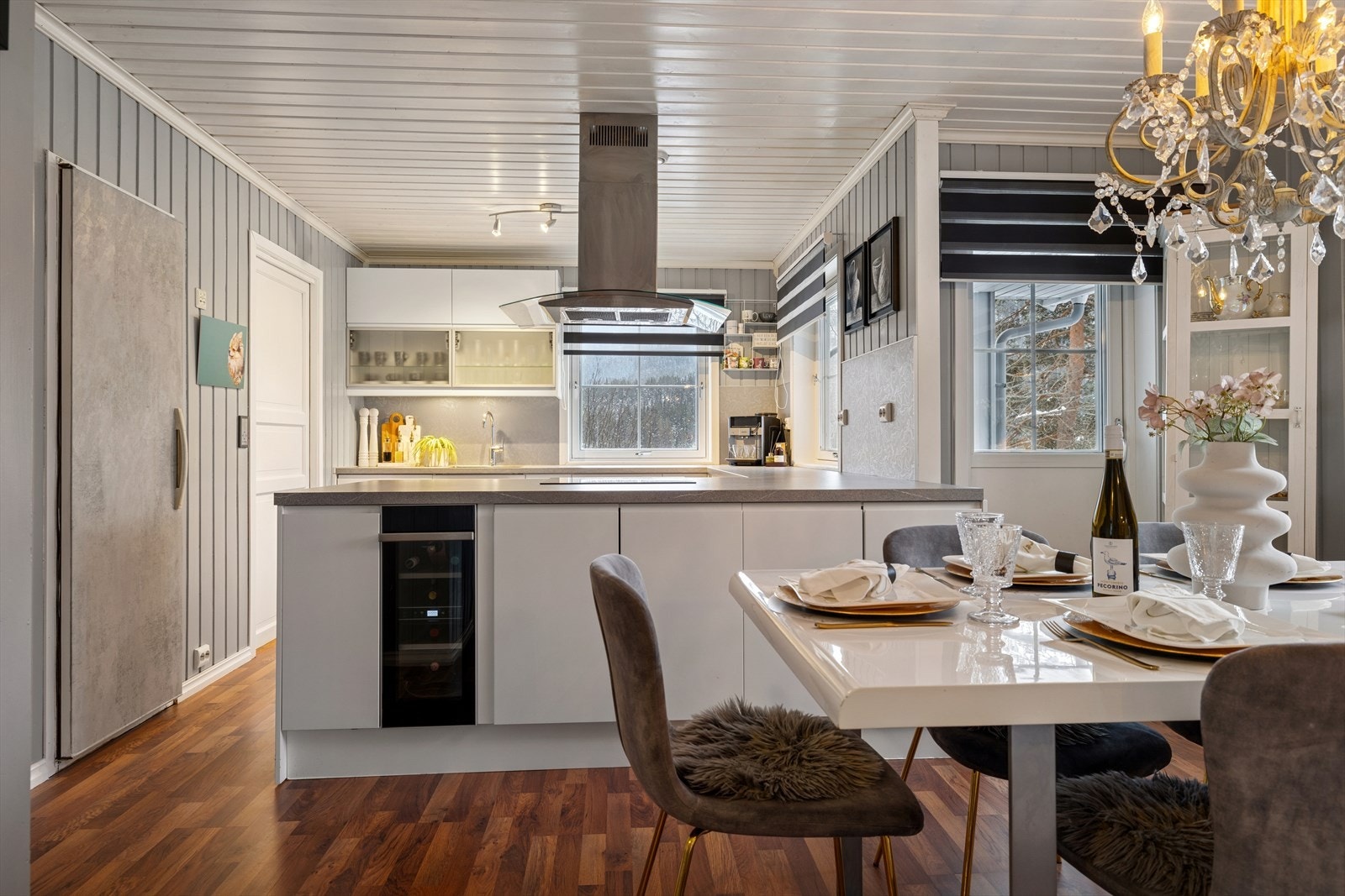 En lys og innbydende kjøkkensone der spiseplass og arbeidsområde flyter sømløst sammen i en helhetlig og gjennomført løsning. Galleribilde