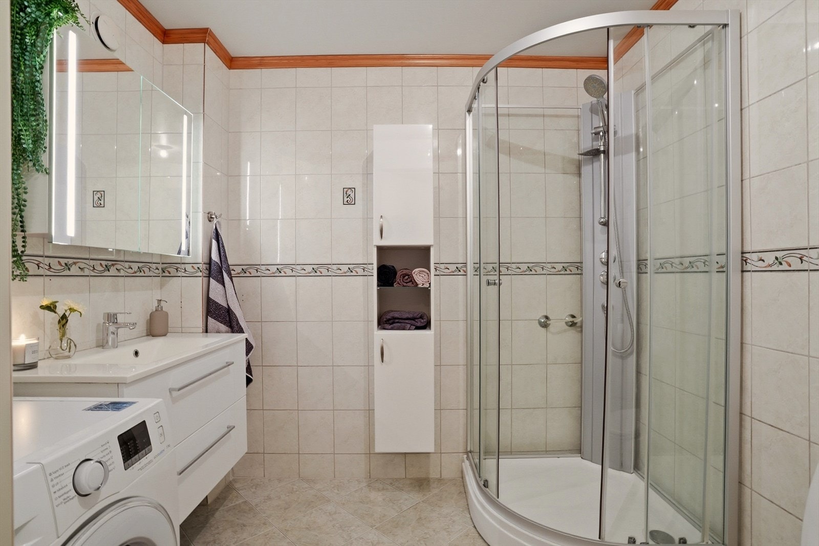 Baderom innredet med toalett, dusjkabinett, servant m/skuffer og opplegg til vaskemaskin. Galleribilde