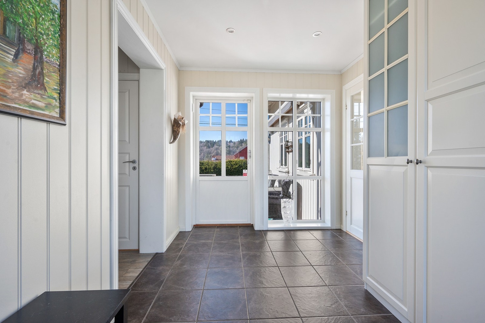 Lyst og romslig inngangsparti i tilbygget (2011/12) med flislagt gulv og varmekabler. Praktisk gjennomgang med utgang til begge sider. Galleribilde