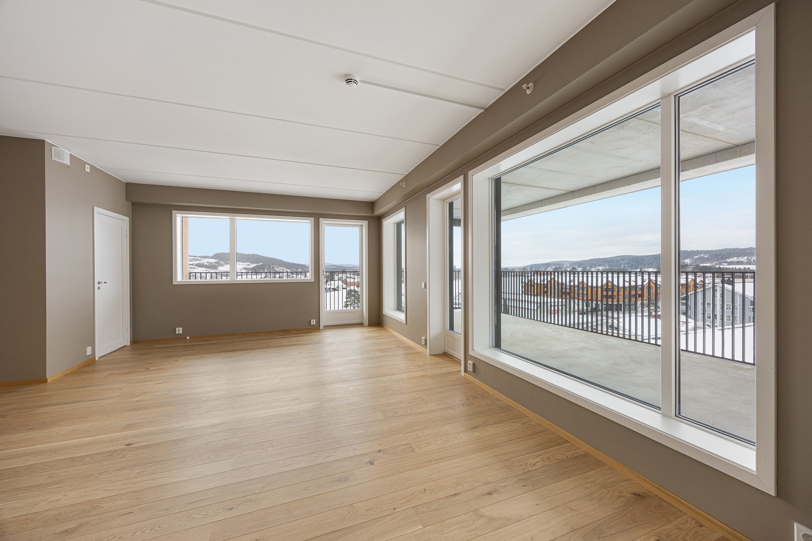 Stue og kjøkken har store vindusflater som slipper inn dagslyset fra to kanter og gir fin utsikt Galleribilde