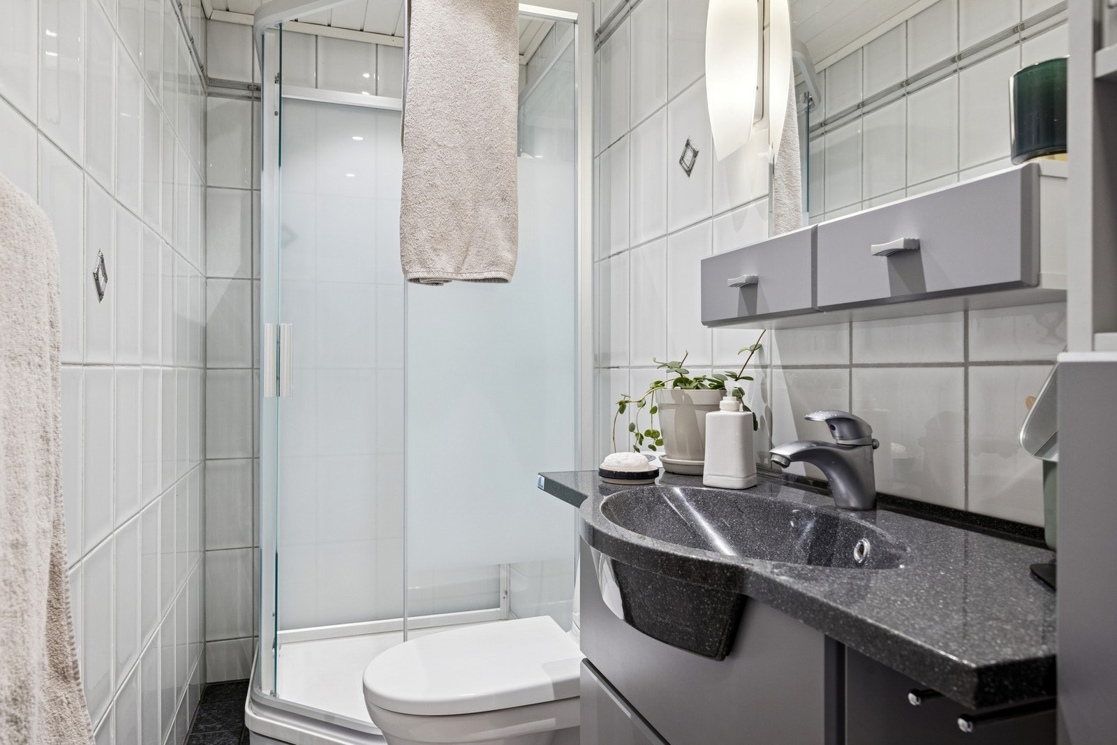 Bad på loft med dusjkabinett, flis på vegger, toalett og baderomsinnredning. Gulvvarme. Galleribilde