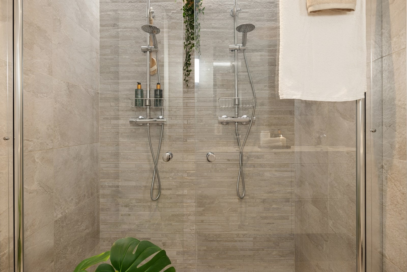 Dusjnisjen har dobbelt dusjgarnityr med regnfall og avlang slukrist langs vegg. Galleribilde